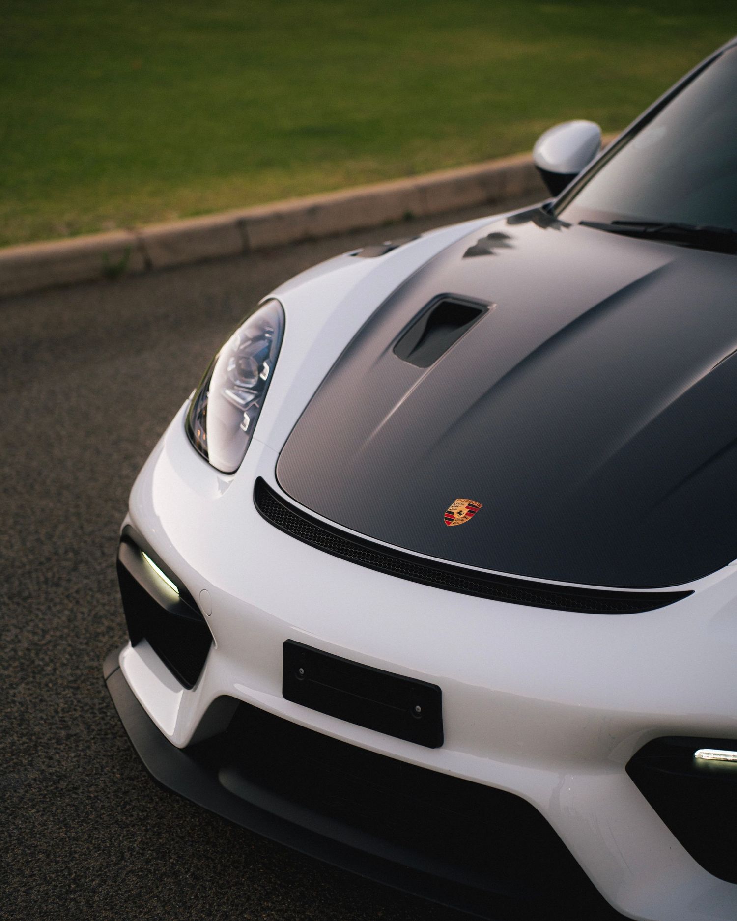 Close-up front view of a white and black Porsche sports car showing distinctive headlight design.