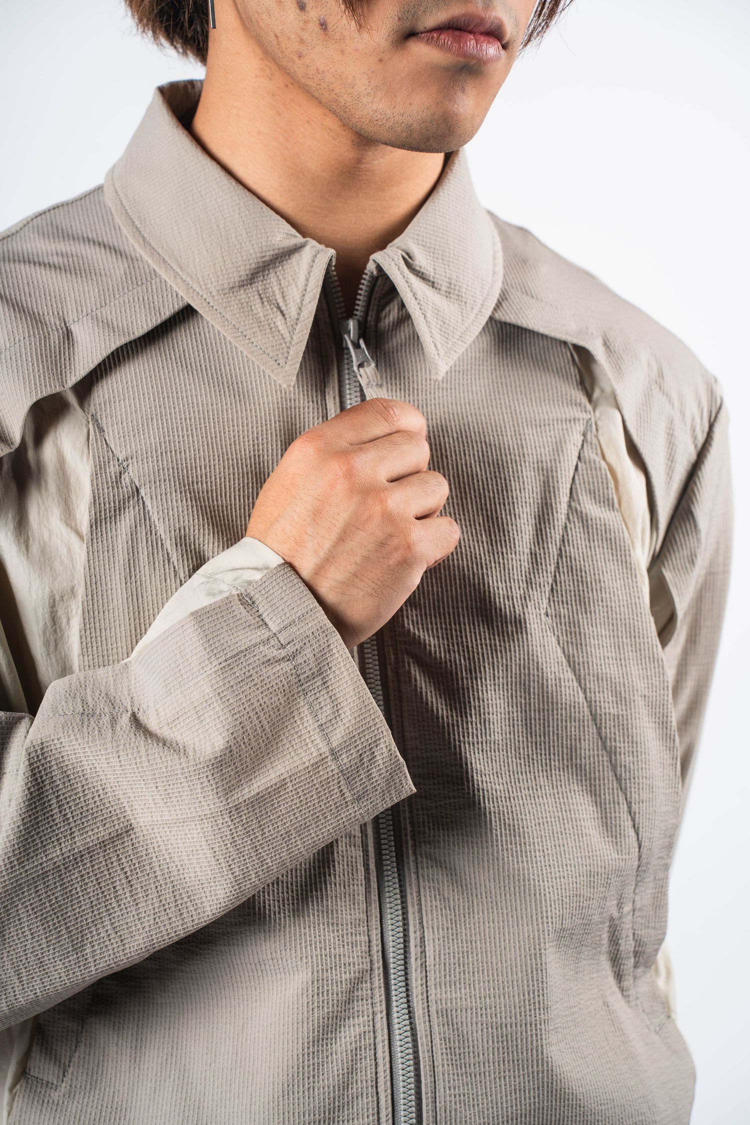Close-up of beige textured zip-up jacket collar and upper torso.