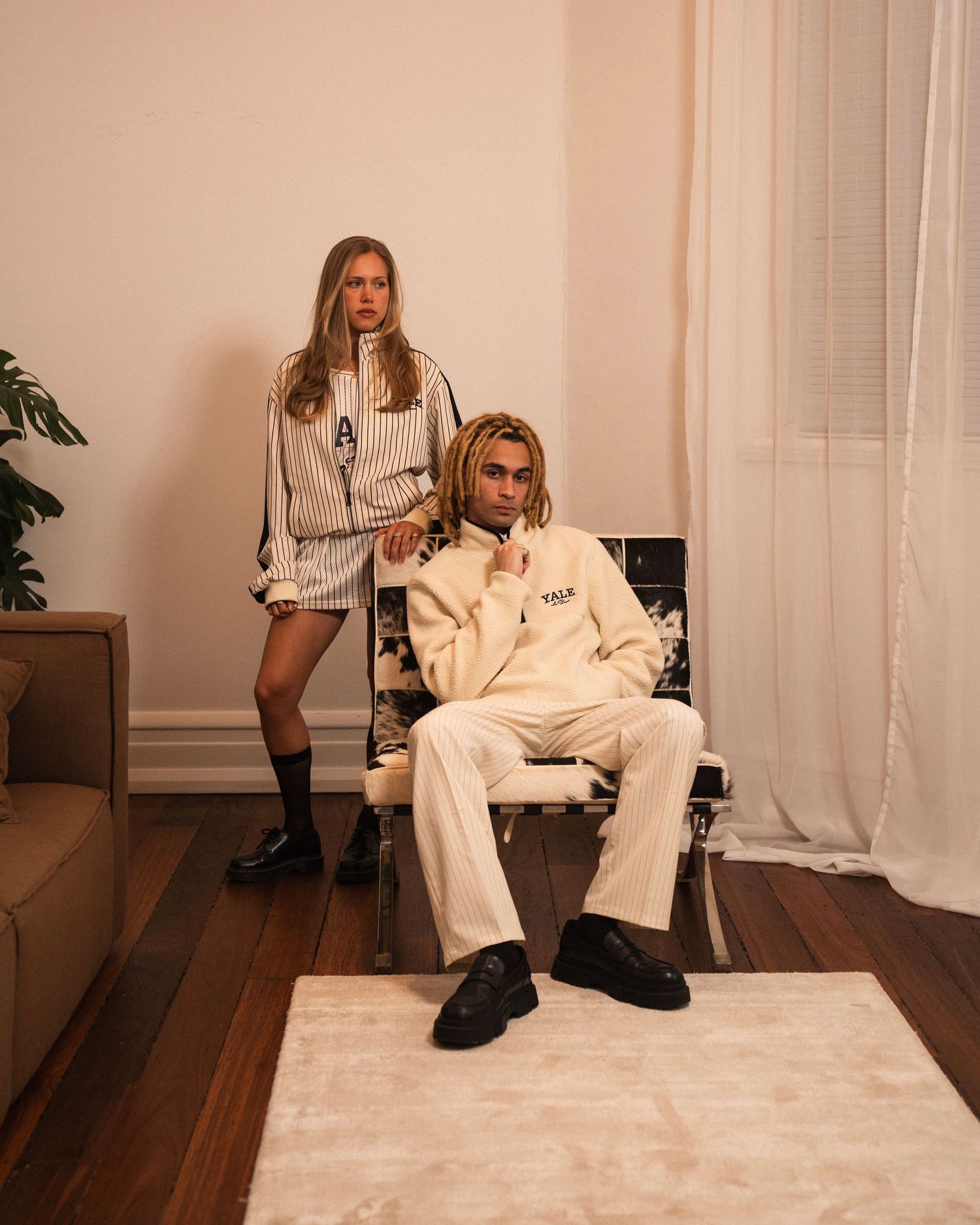 Lifestyle photo of two people in cream colored loungewear posing in modern living room.