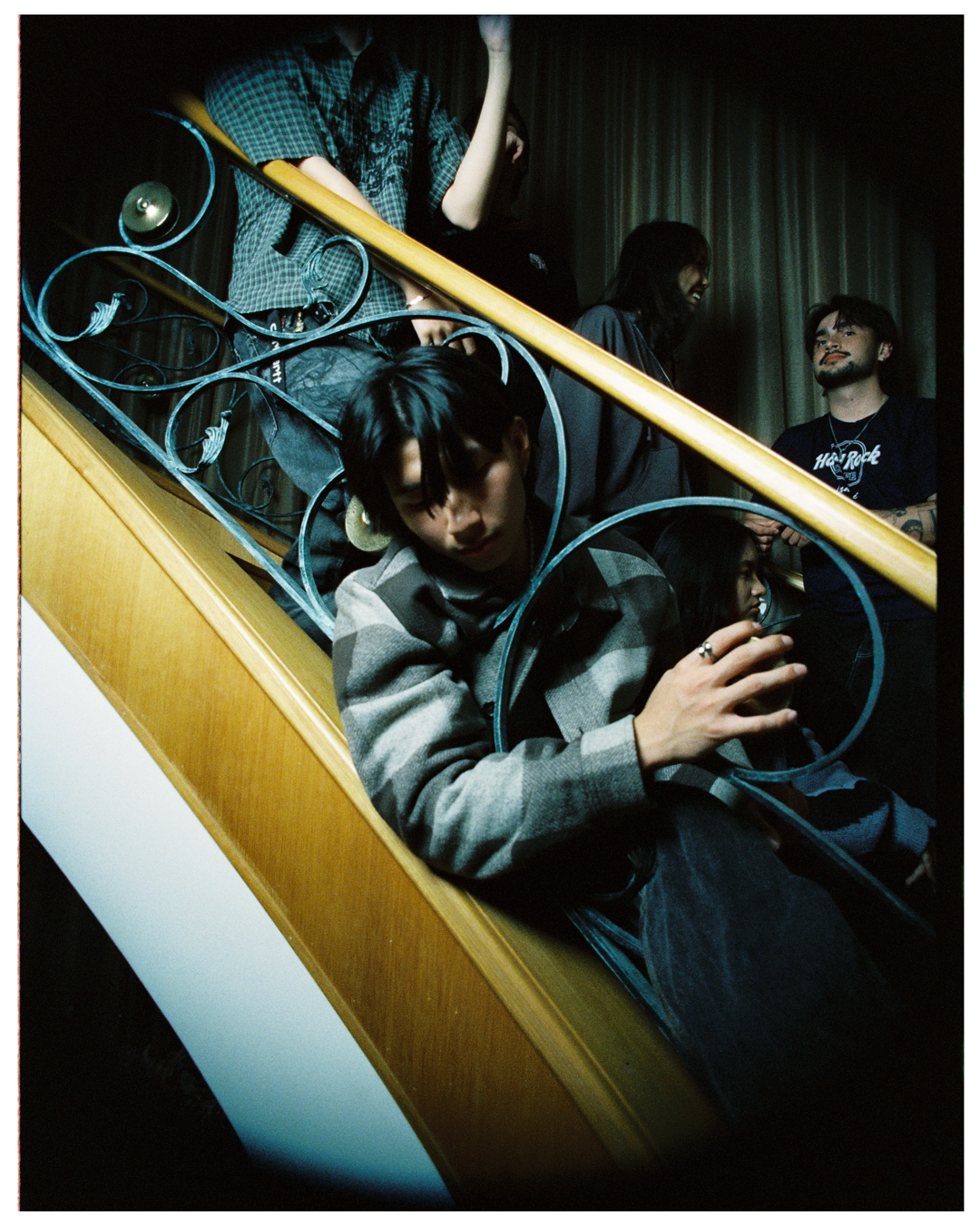 Person in a hoodie ascending ornate blue metallic stairs against a white and gold backdrop with dramatic lighting.