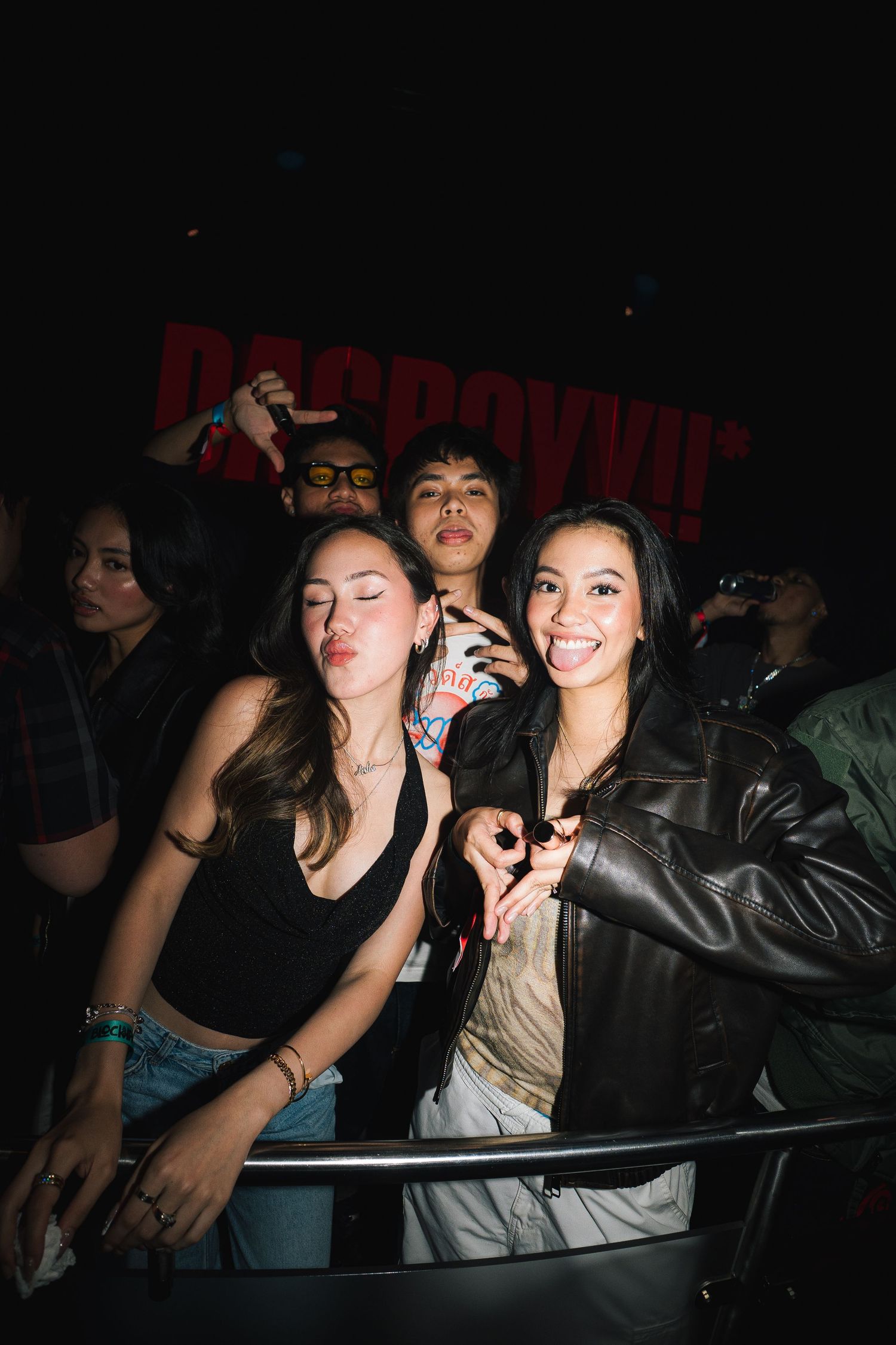 Young people dancing and enjoying themselves at a nightclub with red lighting in a dark atmosphere.