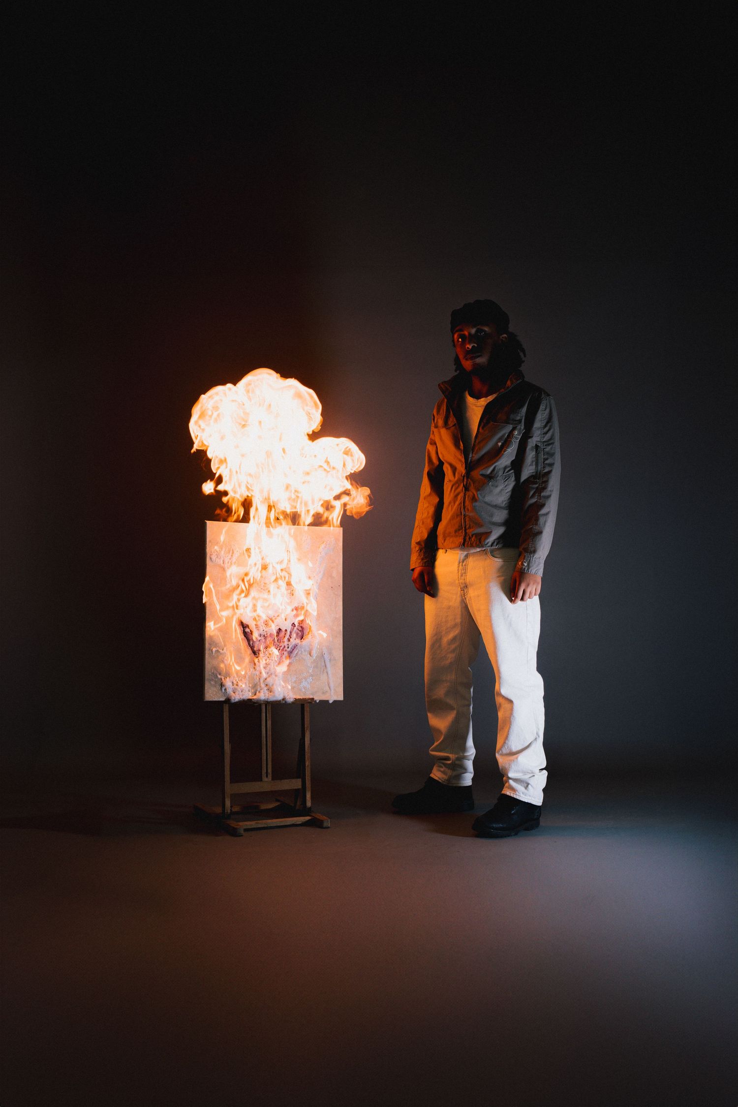 A person in protective gear demonstrates a dramatic fire safety experiment with flames erupting from a clear container.