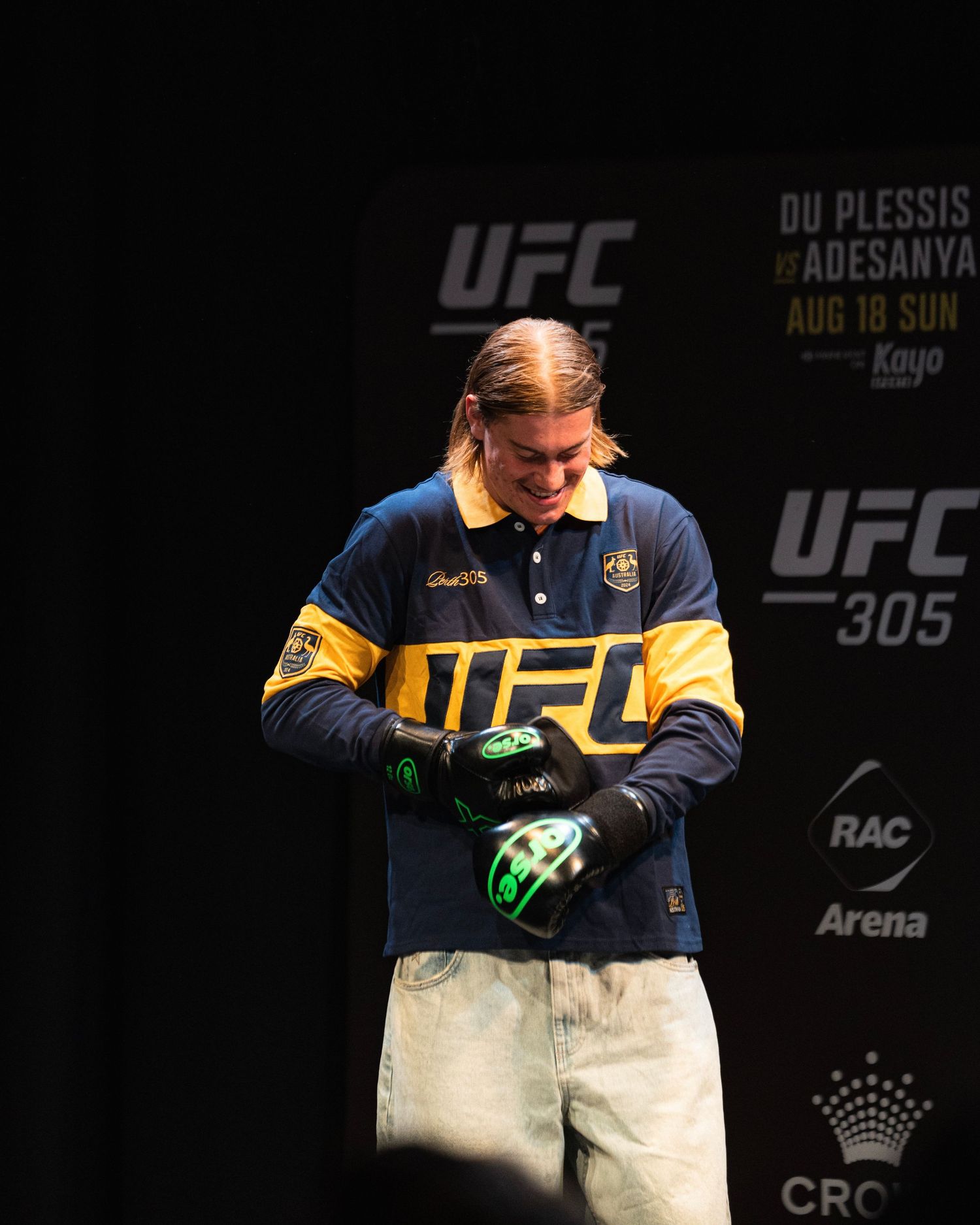 UFC athlete puts on gloves during pre-fight preparations at UFC 305 event.