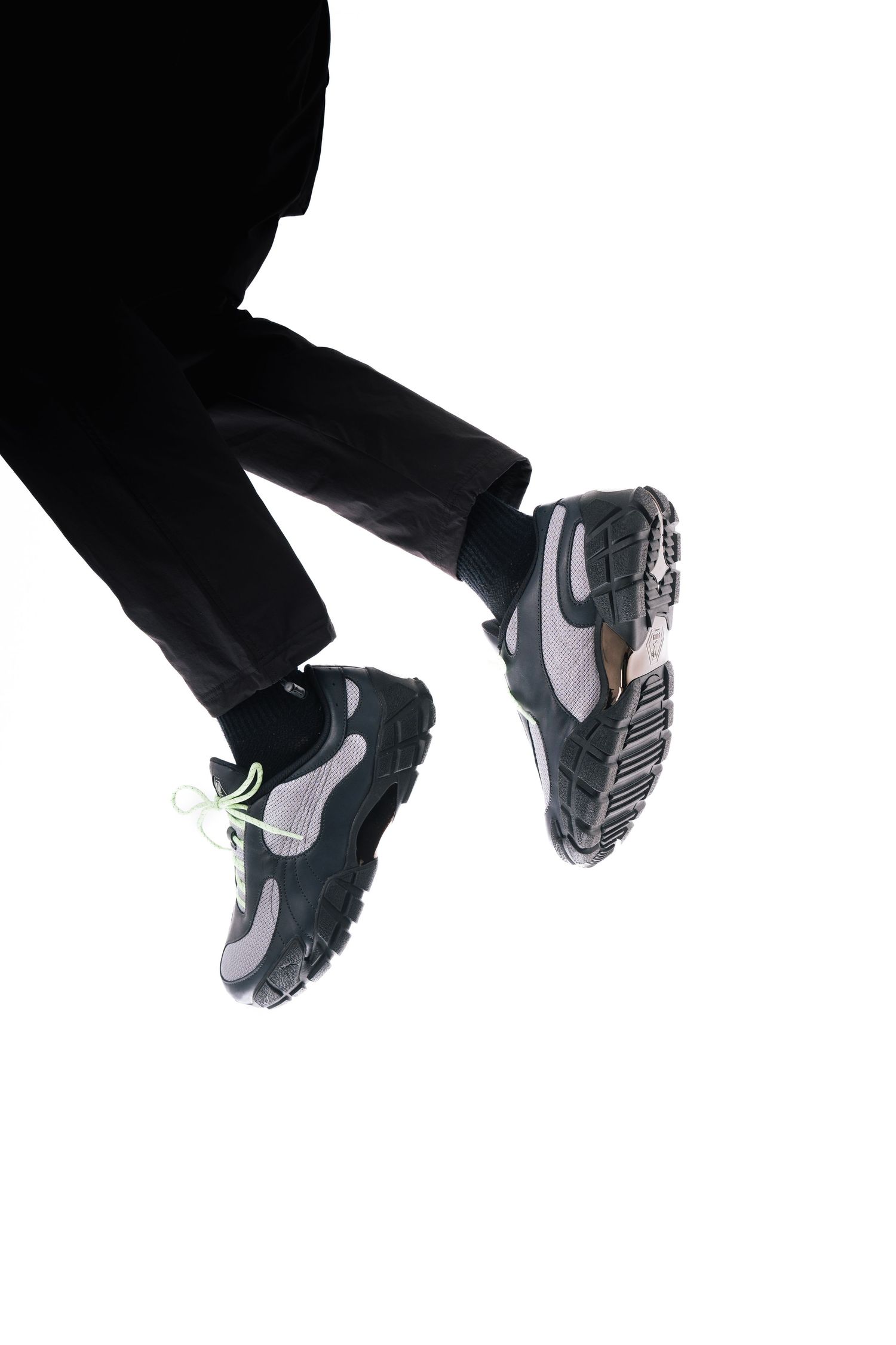 Black silhouette of sneakers against white background in dynamic jumping pose.