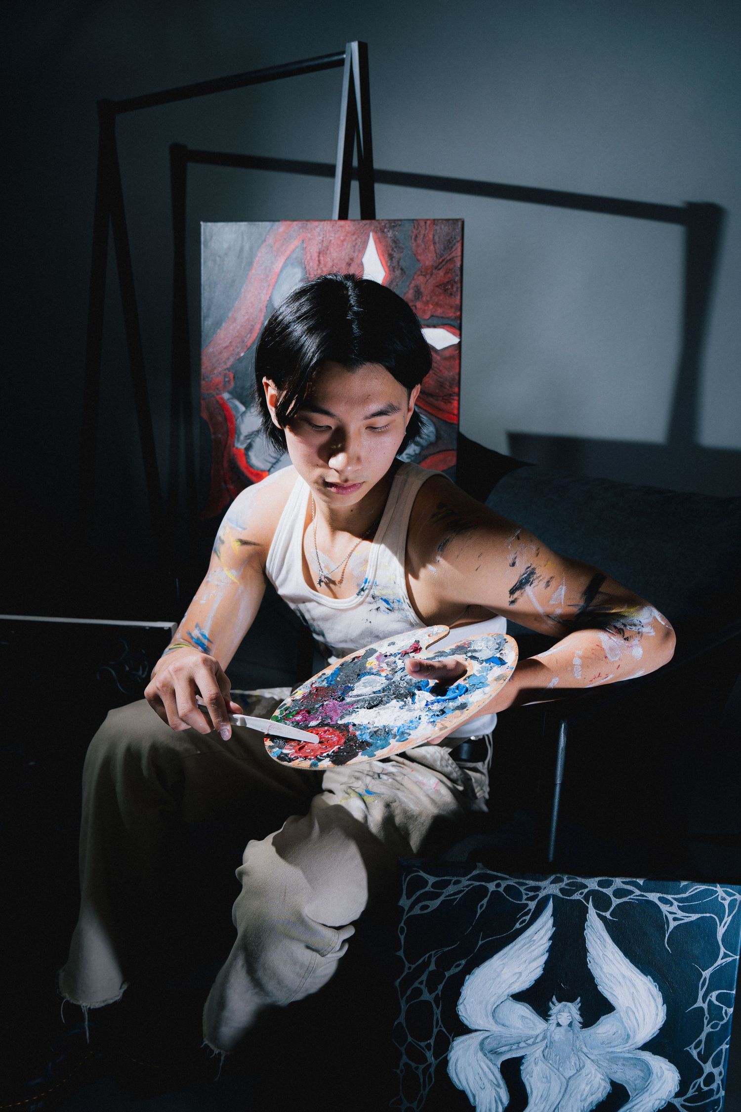Artist working on a detailed textile project using blue dye while sitting in a dimly lit room.