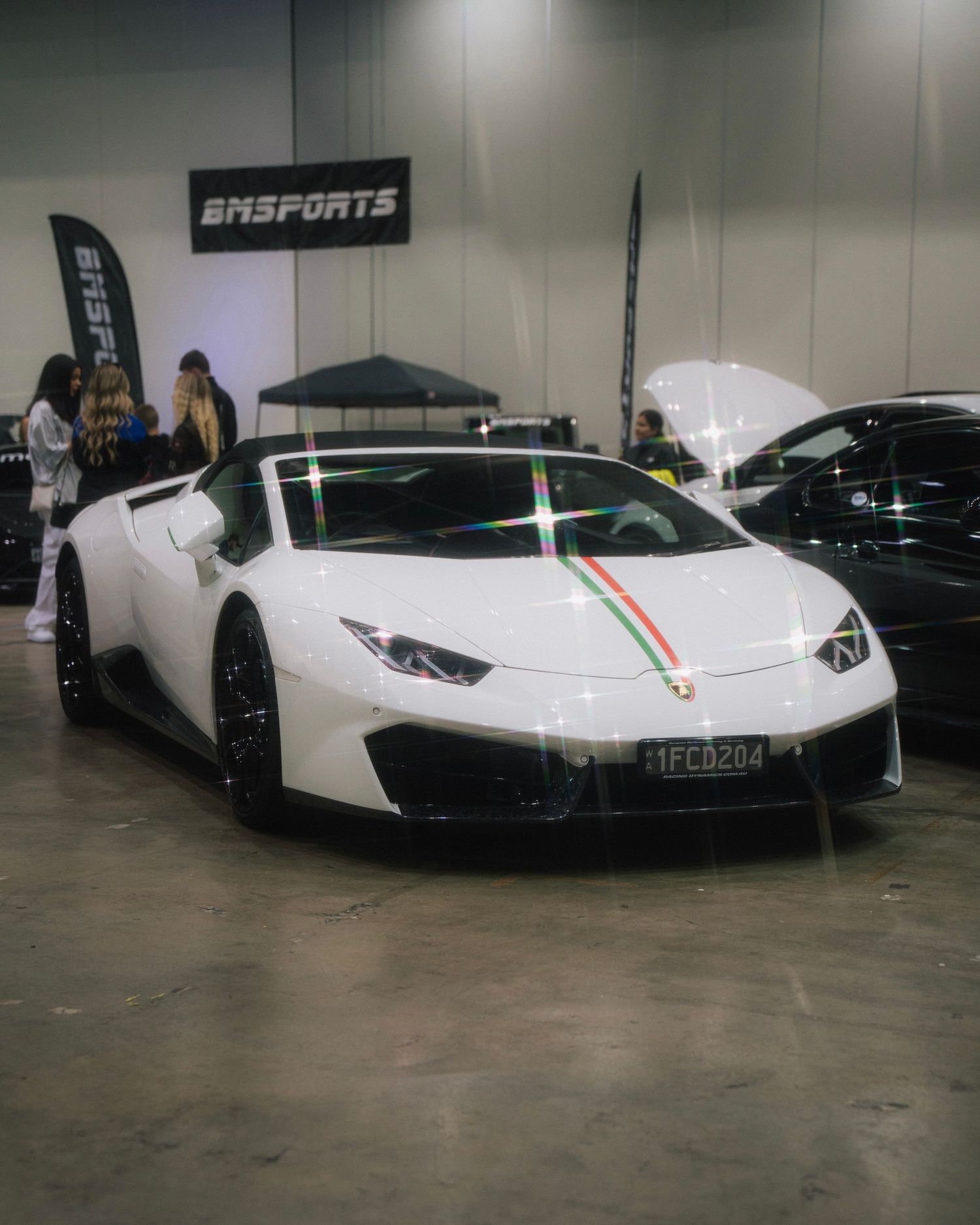 White Lamborghini Huracan with Italian stripe detail displayed at indoor auto show.