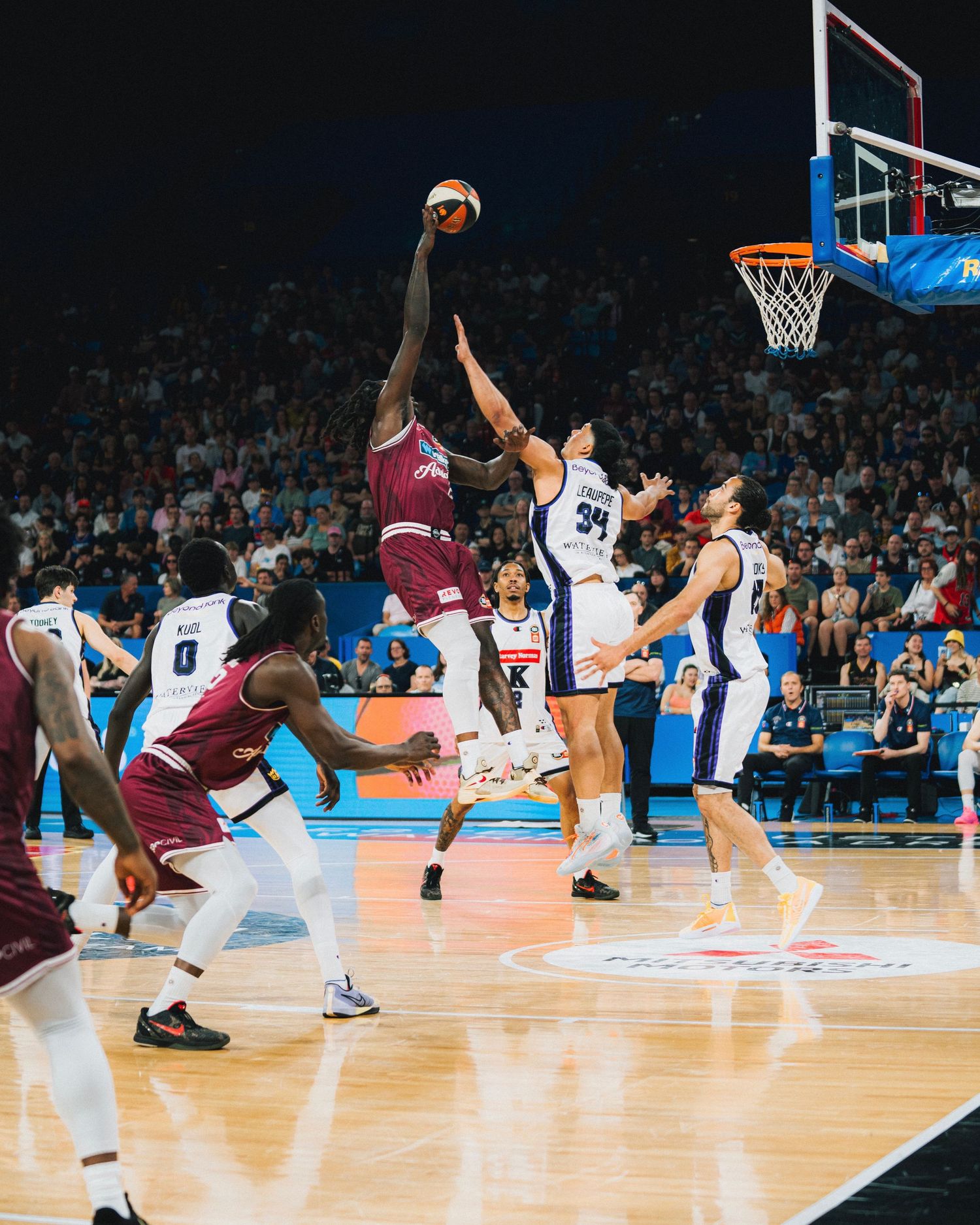 Basketball players jumping for the ball during intense game action on court.