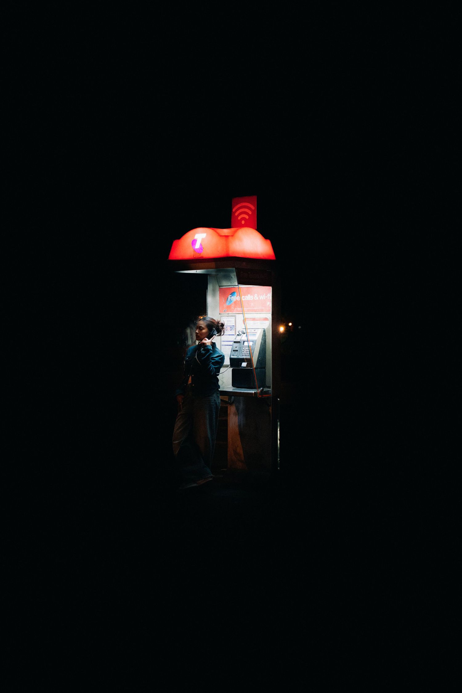 A small illuminated street food vendor booth with a red mushroom-shaped light fixture glows in the dark.