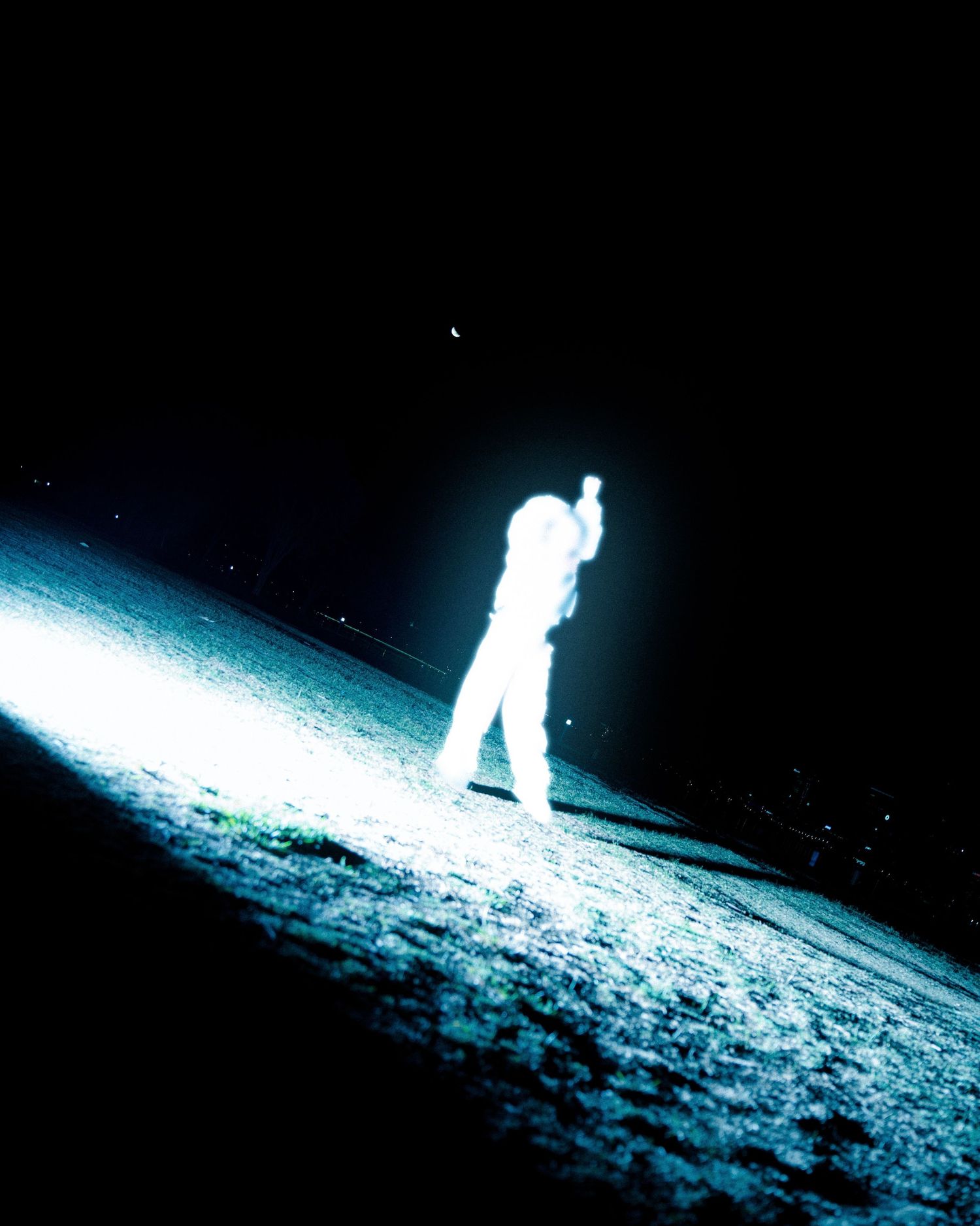 Luminous figure stands on illuminated snowy surface against dark night sky.
