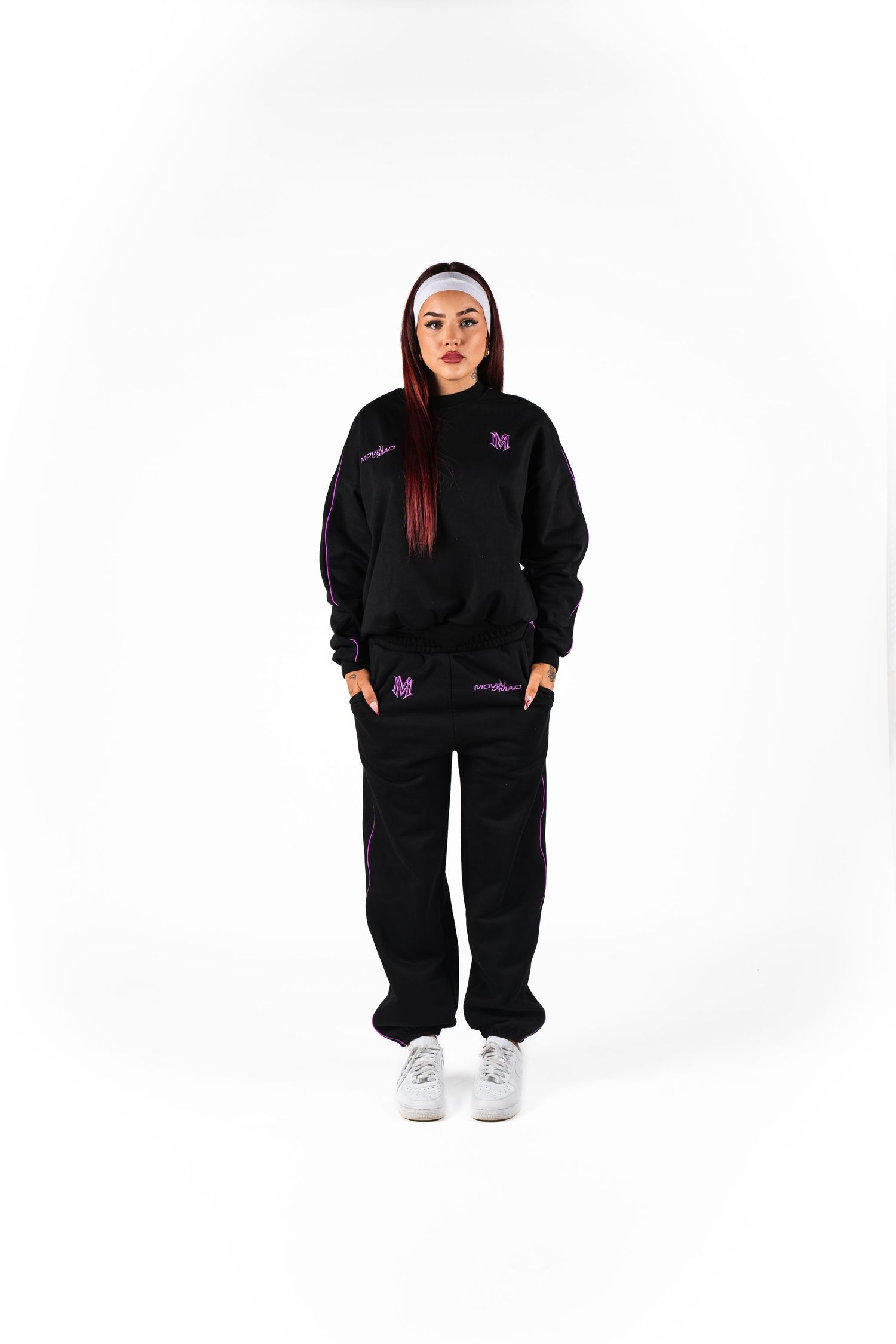 Black tracksuit ensemble with pink accents and white sneakers shown against white background.