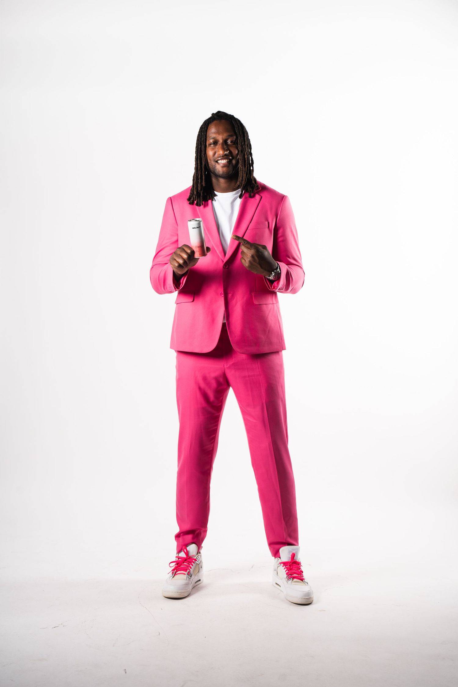 Person wearing a bright pink business suit and white sneakers poses in different angles against a white background.