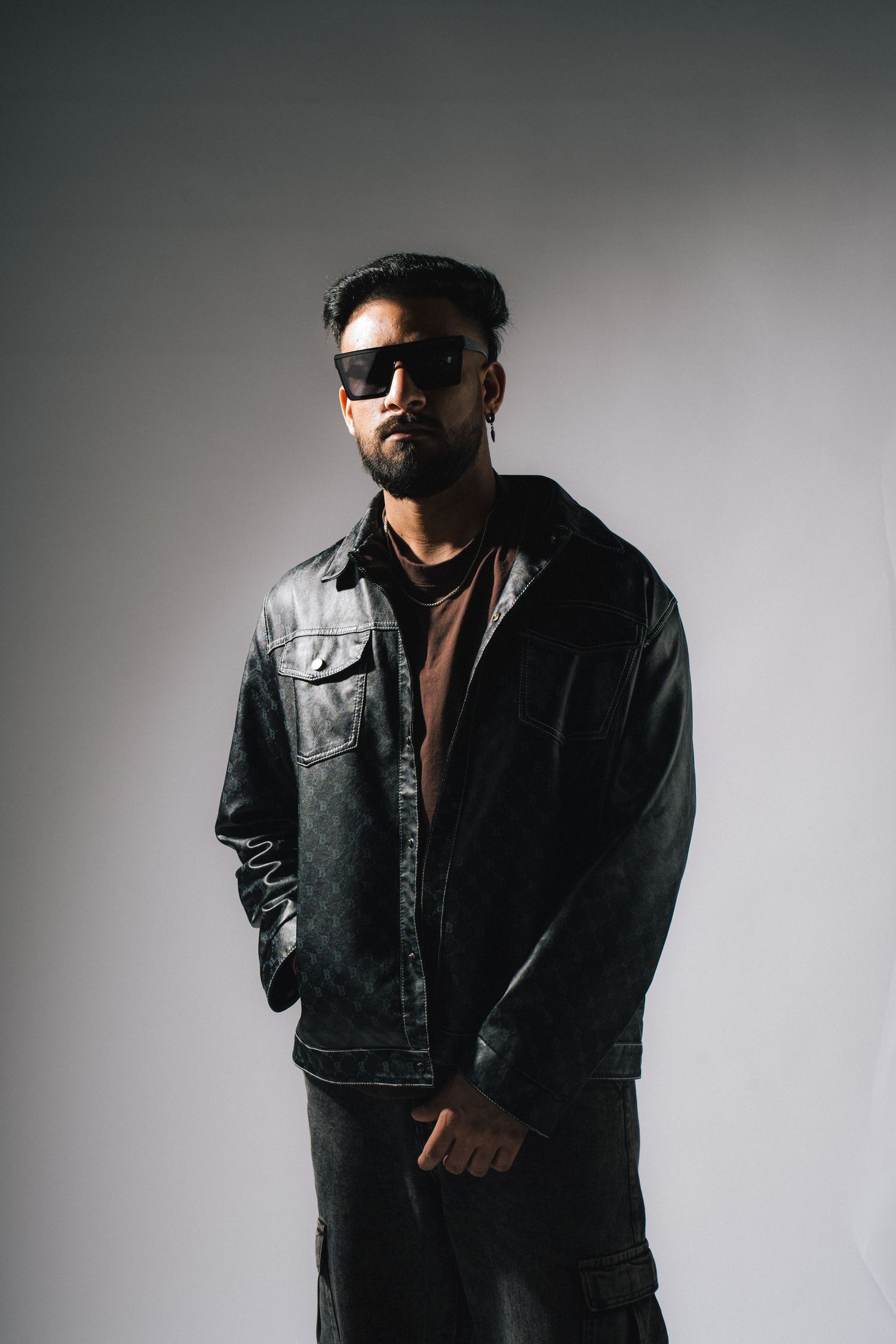 Artistic black and white portrait series showing someone in dark leather jacket and sunglasses against plain backdrop.