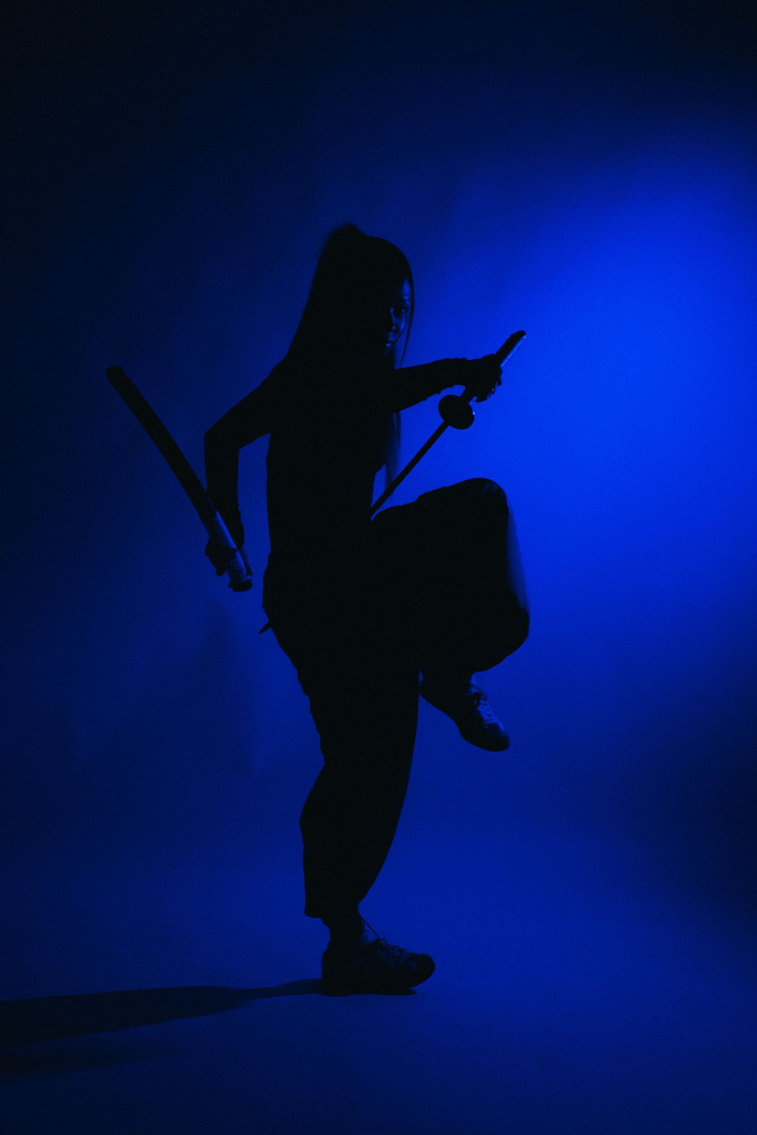 A silhouetted figure leaps through the air against a deep blue background creating a dynamic dance pose.