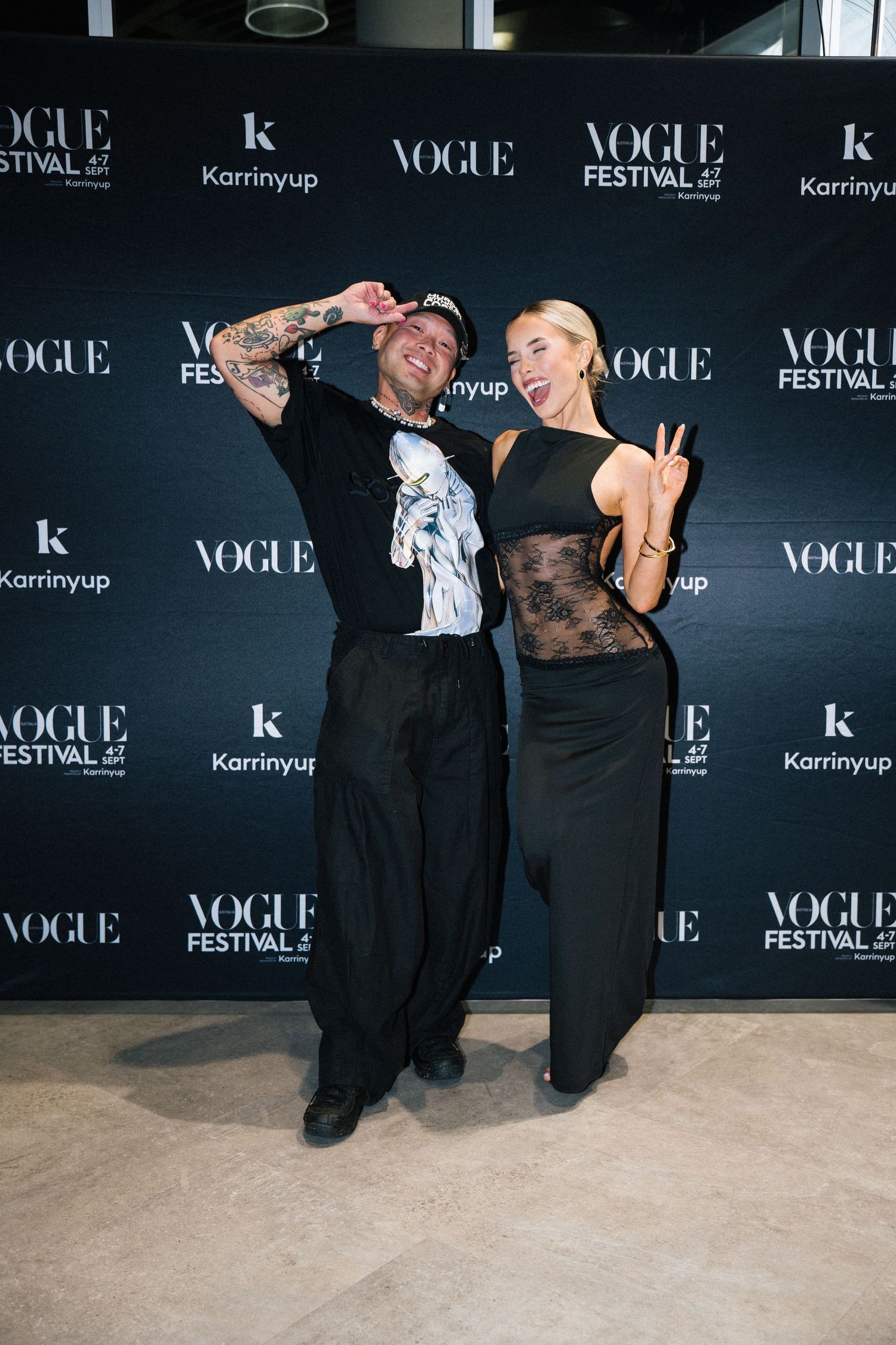 A group poses playfully against a black Vogue step-and-repeat wall at a fashion event.