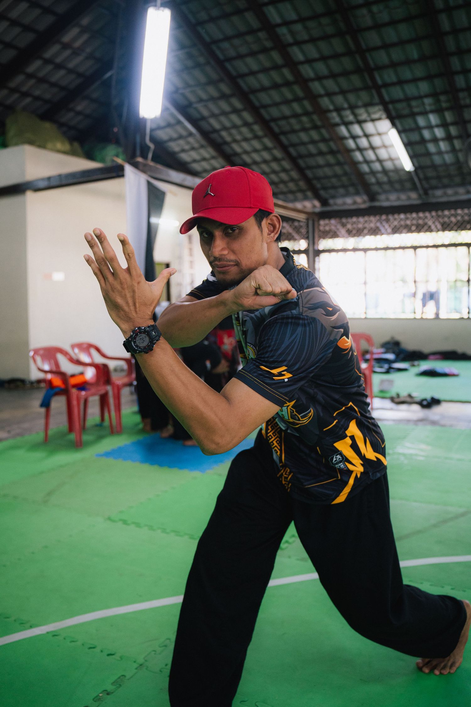 Martial artist in red cap demonstrates defensive stance during training session.