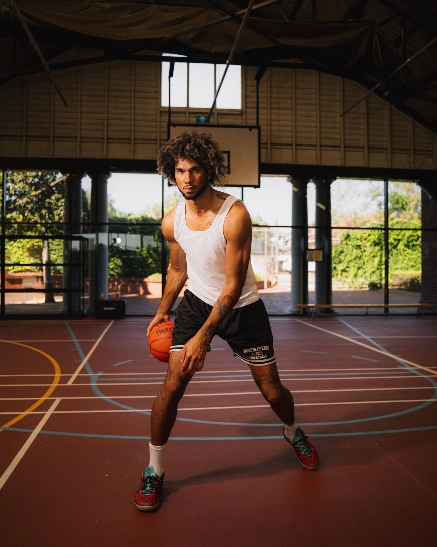 Basketball player dribbling on an indoor court in athletic attire.