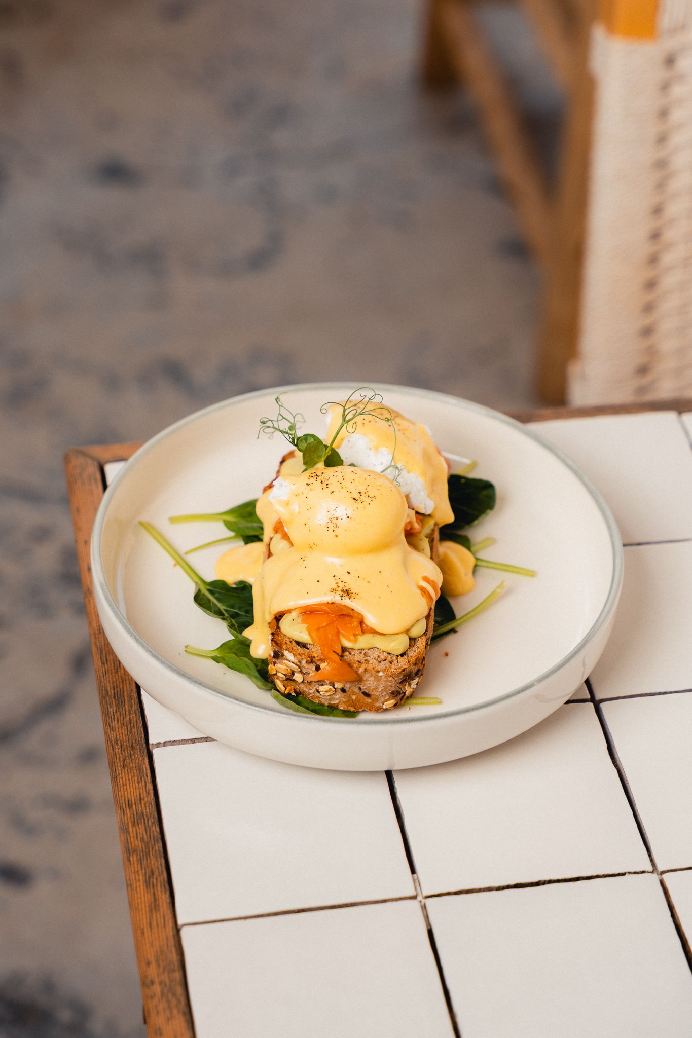 Eggs Benedict with hollandaise sauce served on white plates against a wooden surface.