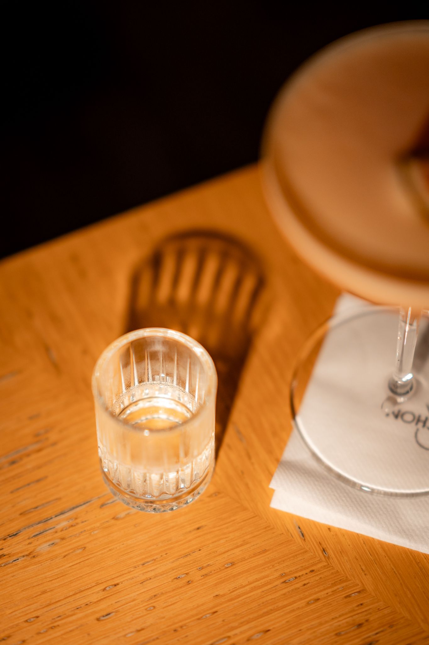 Candlelight glows in a crystal glass on a wooden table with soft focus.