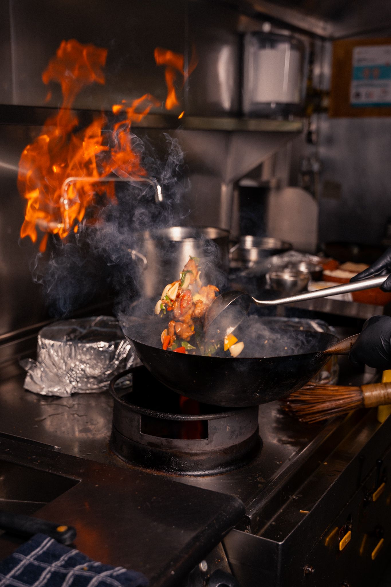 Dramatic shots of flames and smoke rising from pans in a professional restaurant kitchen.