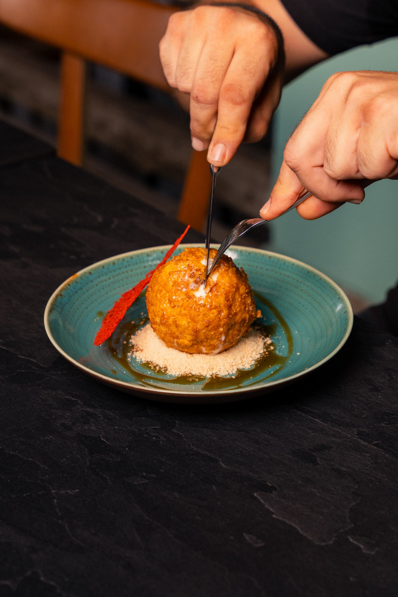 Step-by-step sequence of hands plating and cutting into a golden-crusted gourmet dish on a turquoise plate.