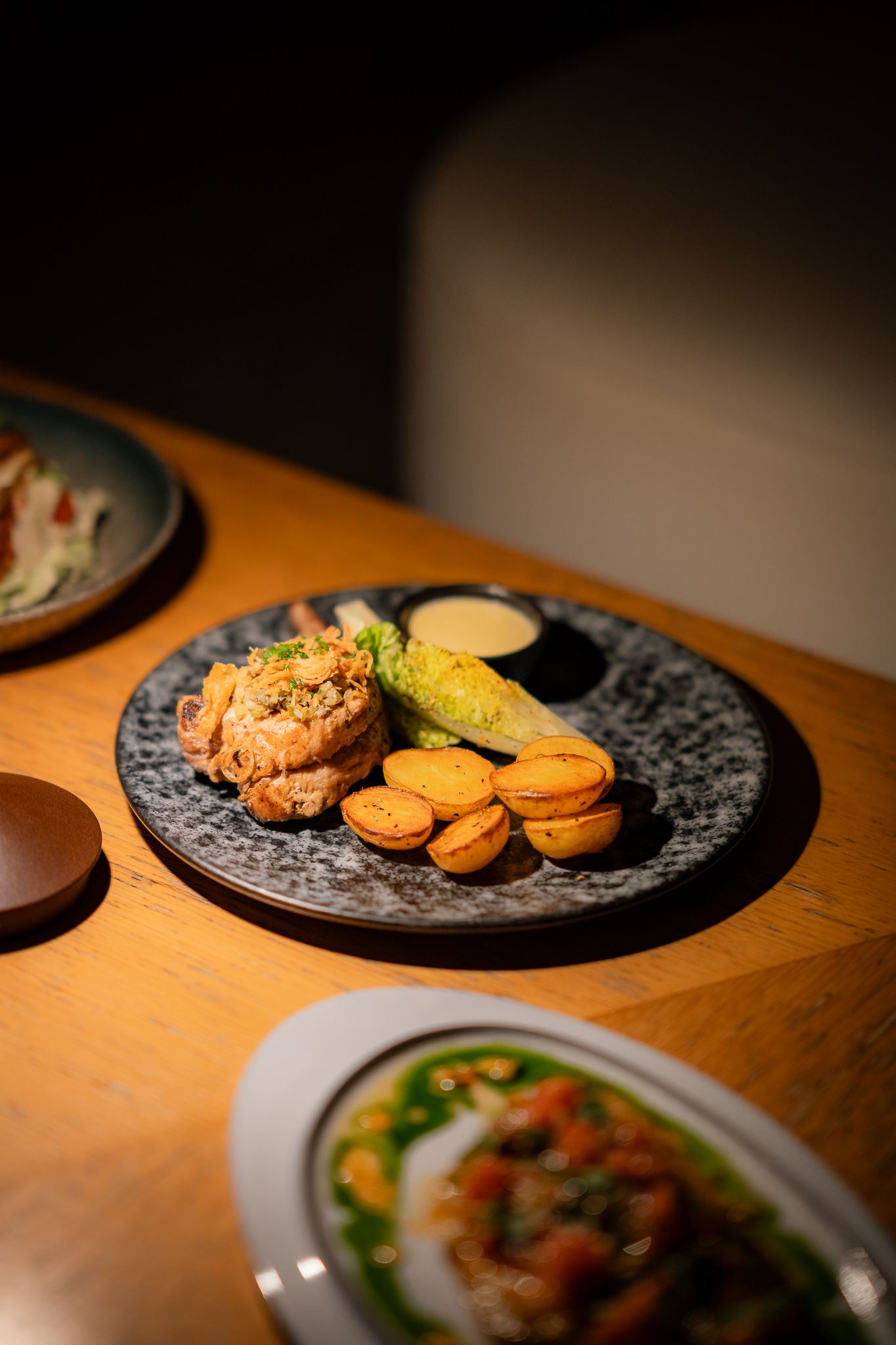 Assorted cookies and desserts arranged on dark decorative plates on a wooden table in warm lighting.