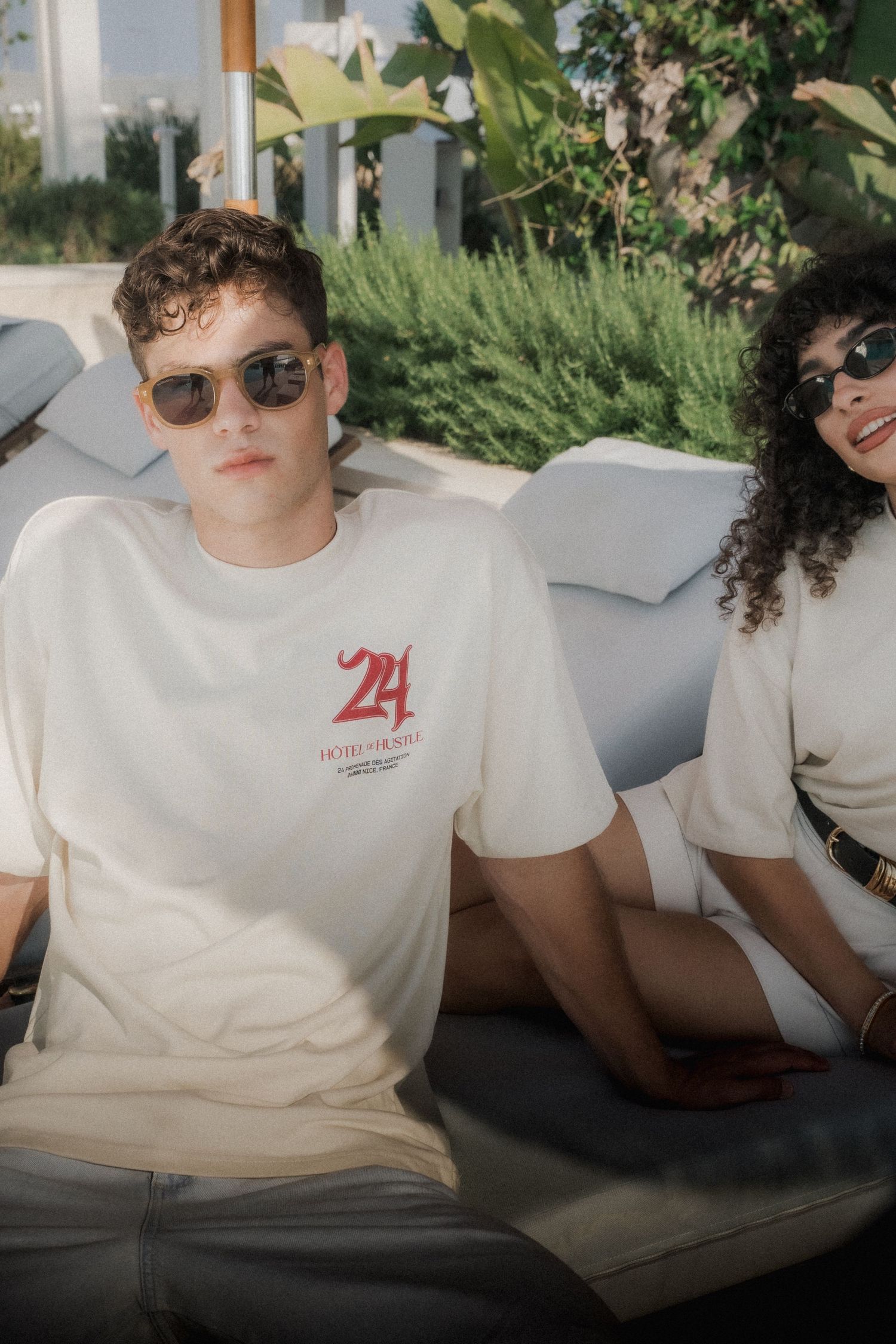 Two people relaxing on outdoor furniture wearing matching casual white t-shirts.