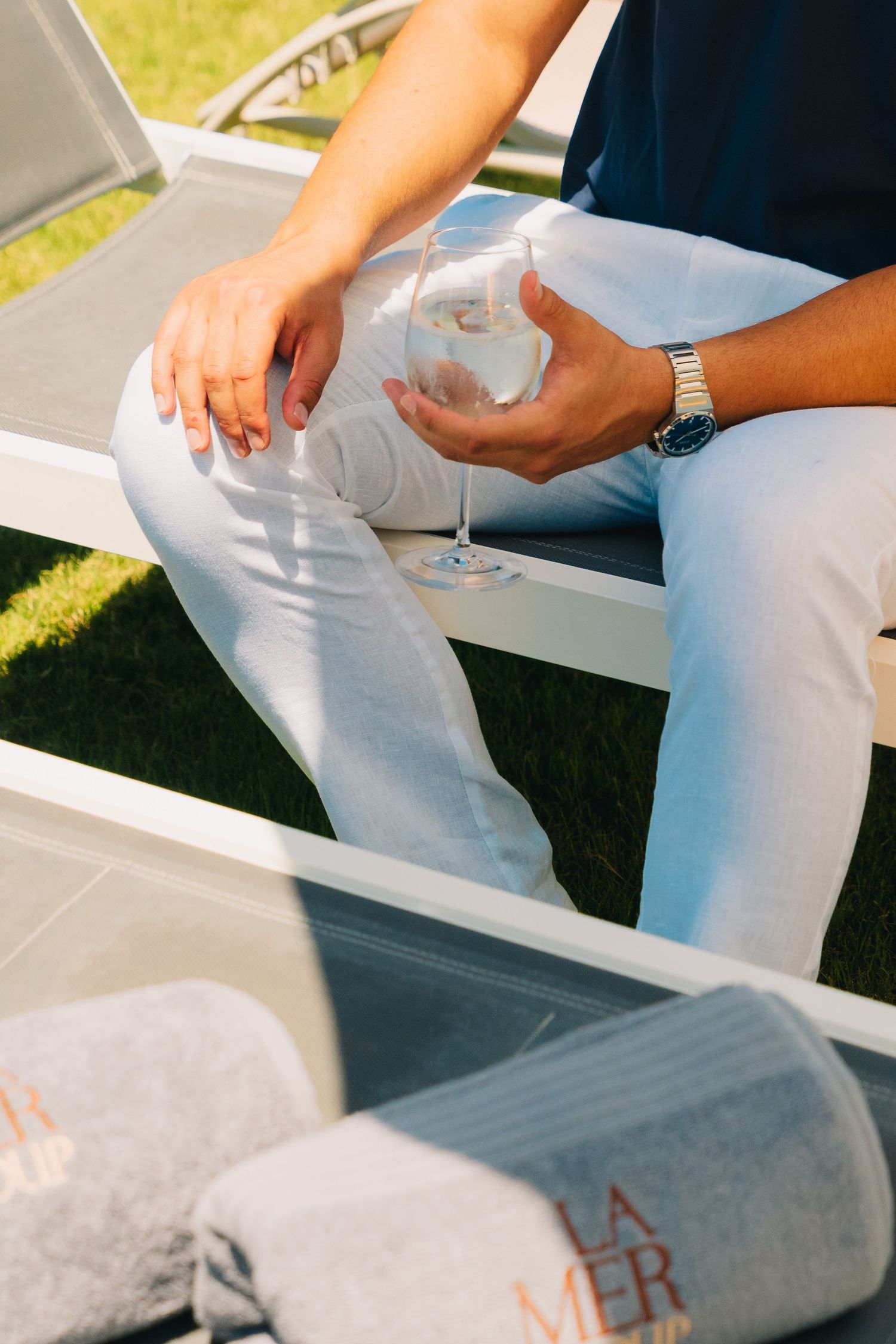 Close-up of hands holding drink while sitting on white outdoor furniture.