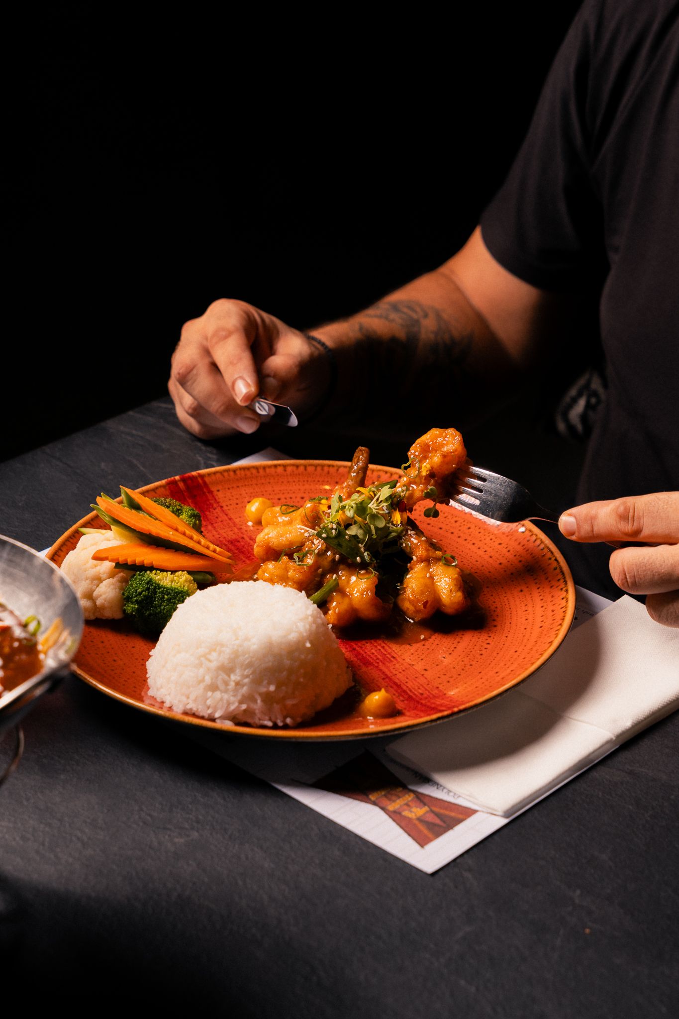 Orange plates with curry and rice dishes photographed on dark background in dramatic lighting.