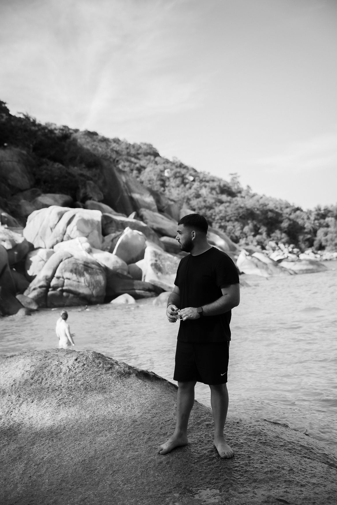 A silhouette of someone standing on rocky terrain near a body of water.