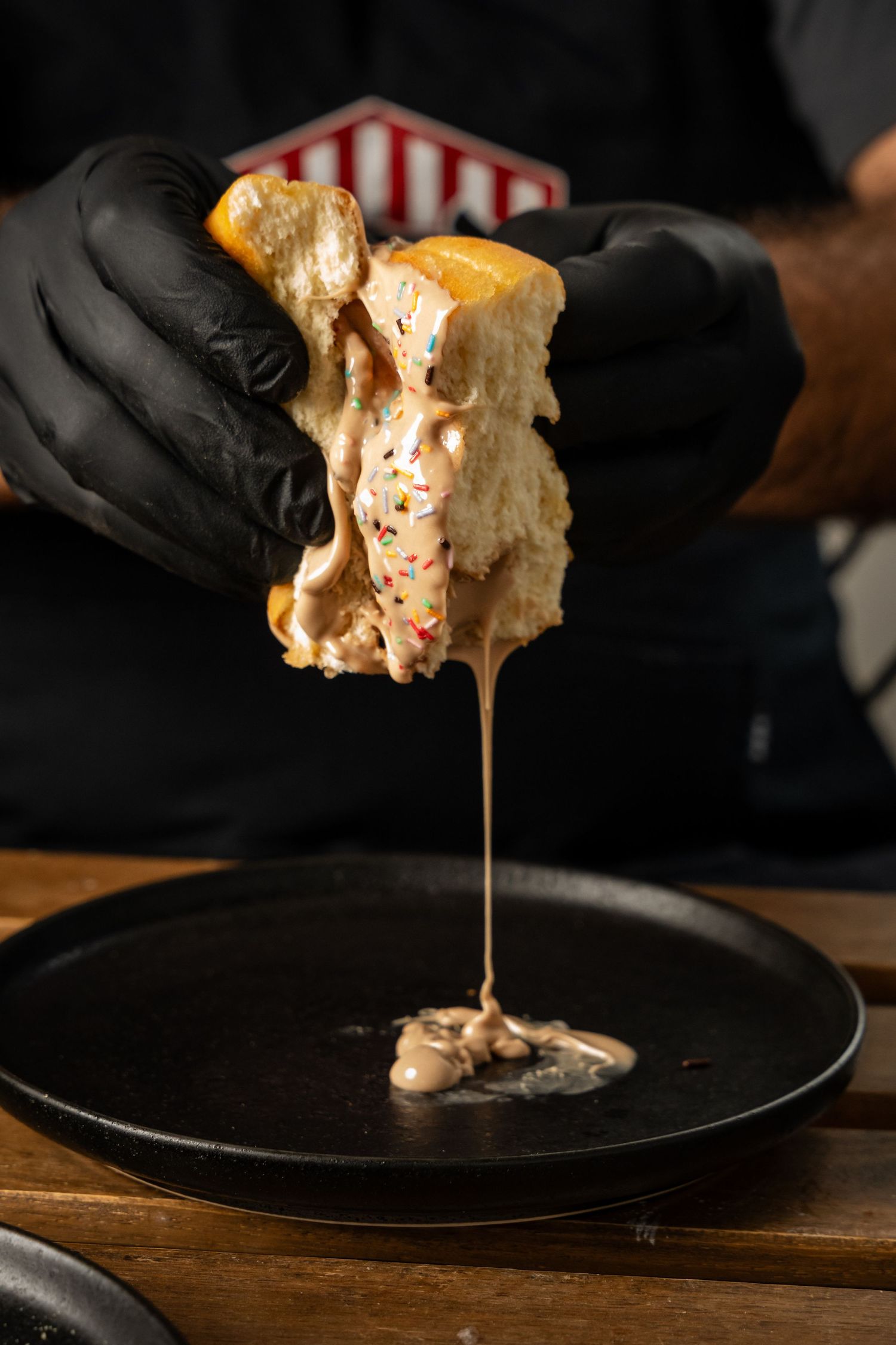 Melted cheese stretches between halves of a grilled sandwich held with black gloves.