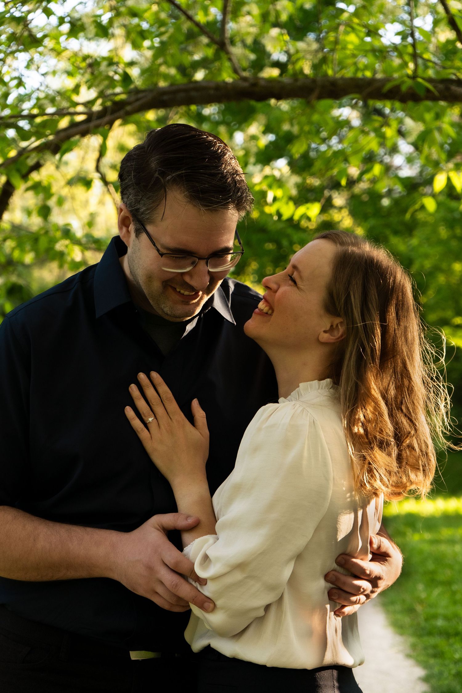 Romantic garden photoshoot with couple embracing under green leafy canopy.