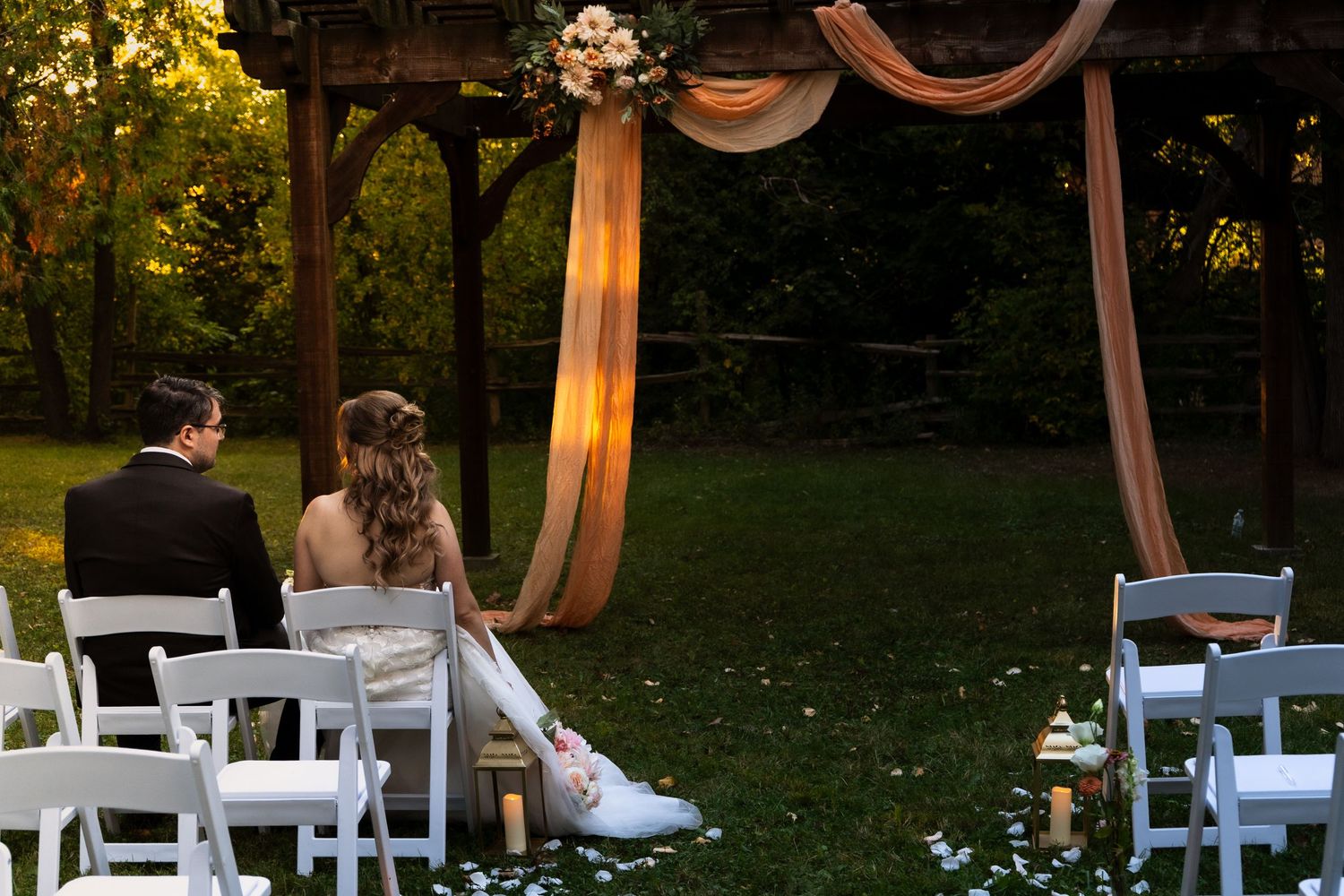 bride and groom sit at the empty ceremony site