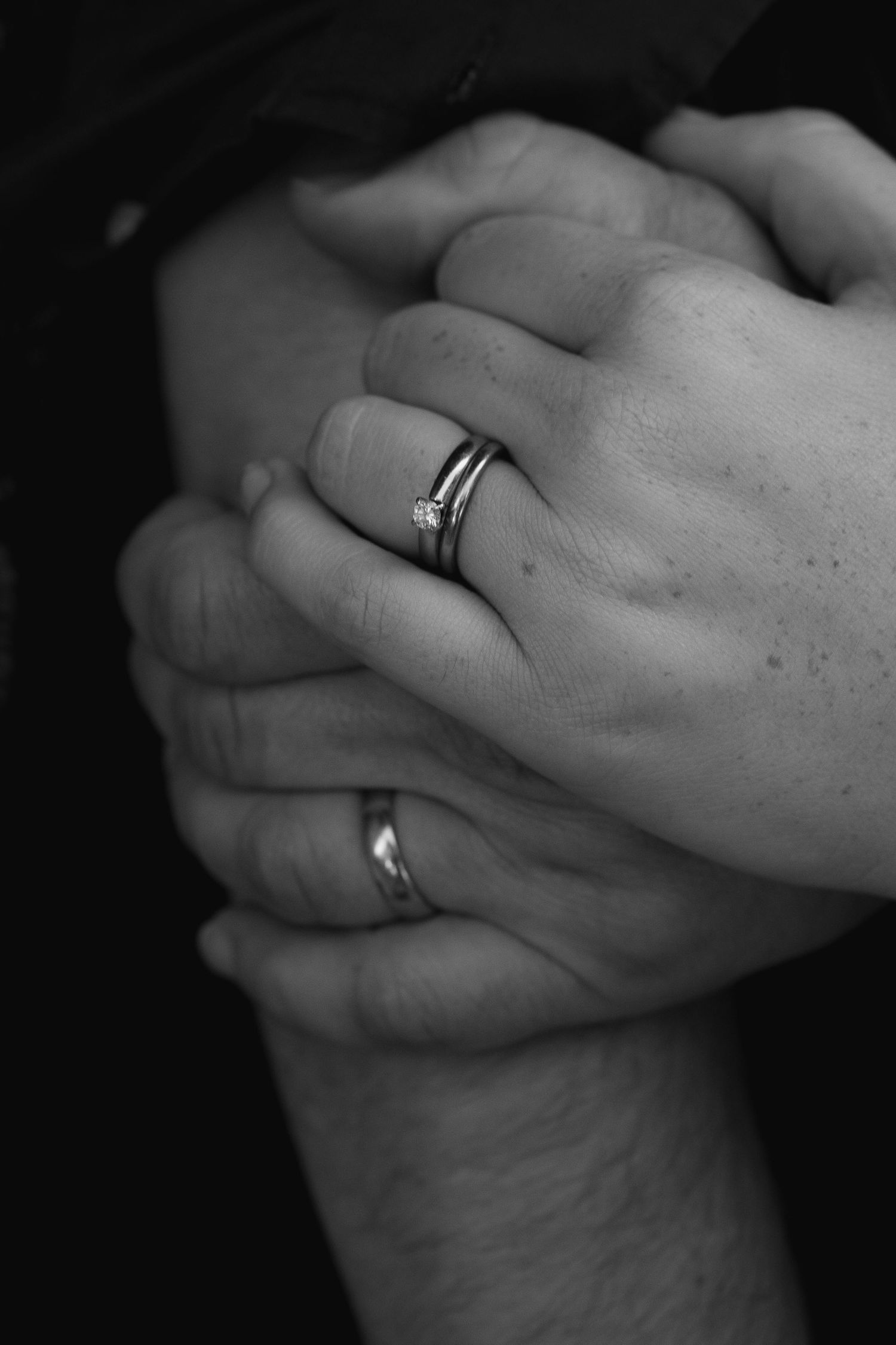 Black and white close-up images of hands holding each other with engagement rings showing romance and commitment.