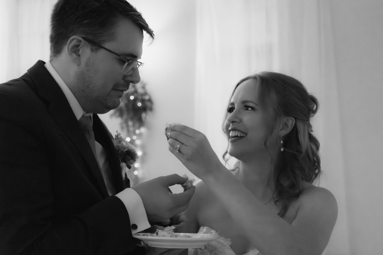 bride and groom in black and white sharing cake