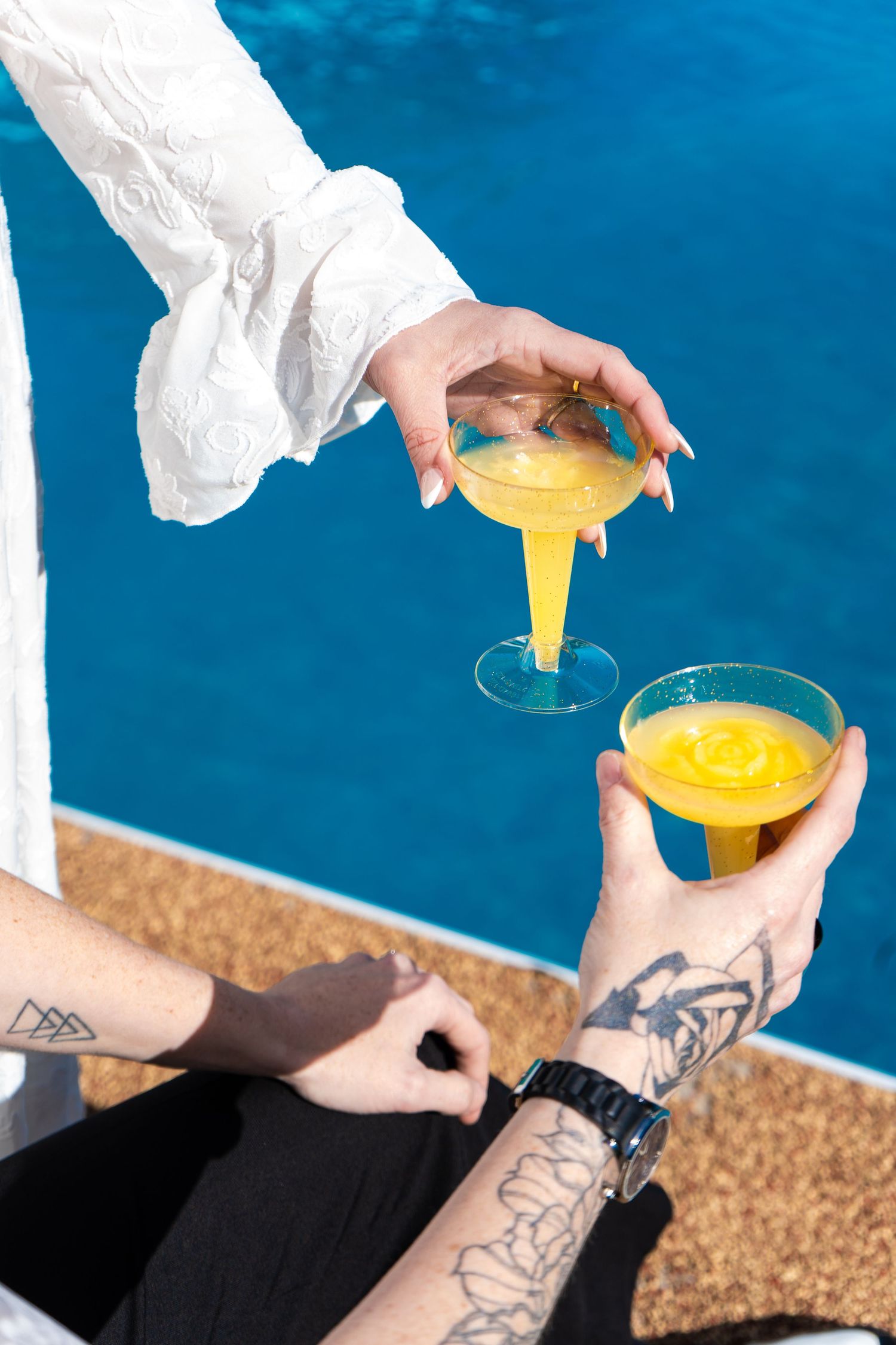 A sequence of hands pouring yellow liquid into glasses against a blue background.