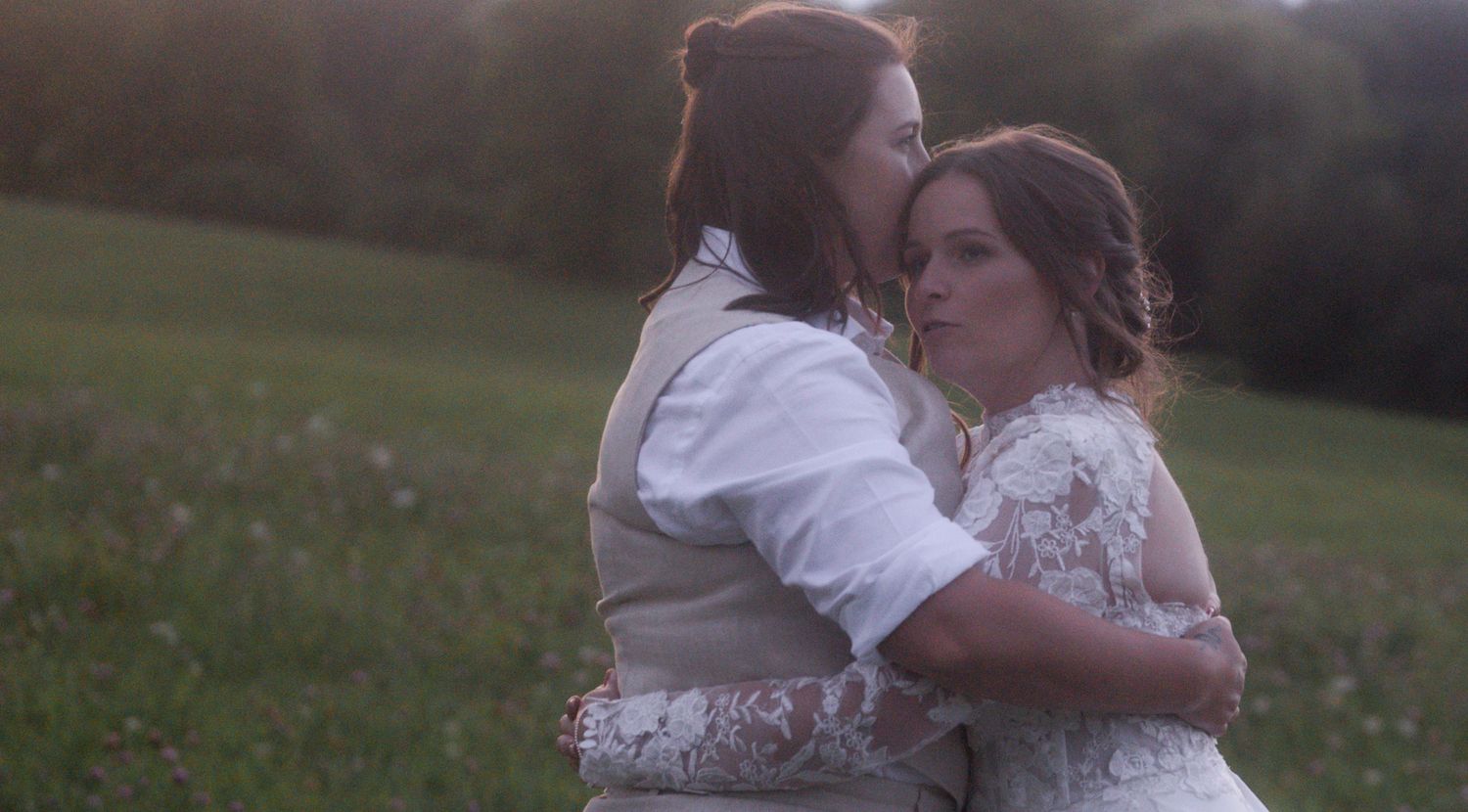 Intimate moment between newlyweds in a sunset-lit field.