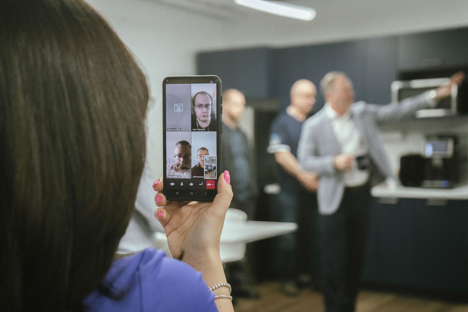 Multiple video conference screens showing remote collaboration in a professional office environment.