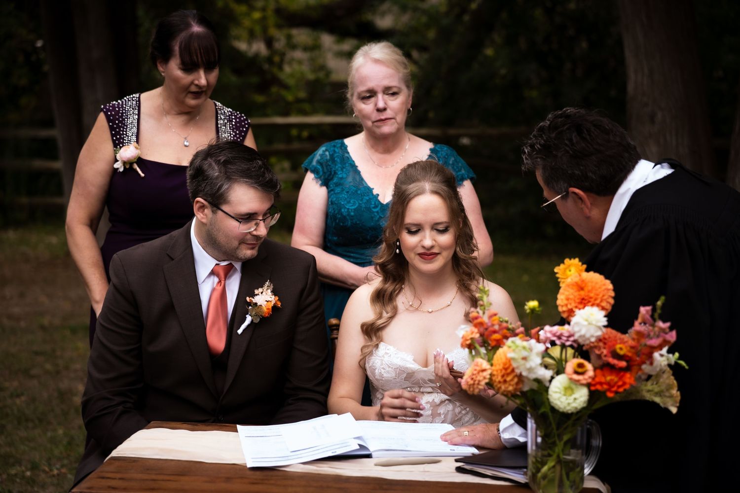 bride and groom signing papers with mother of the bride and mother of the groom