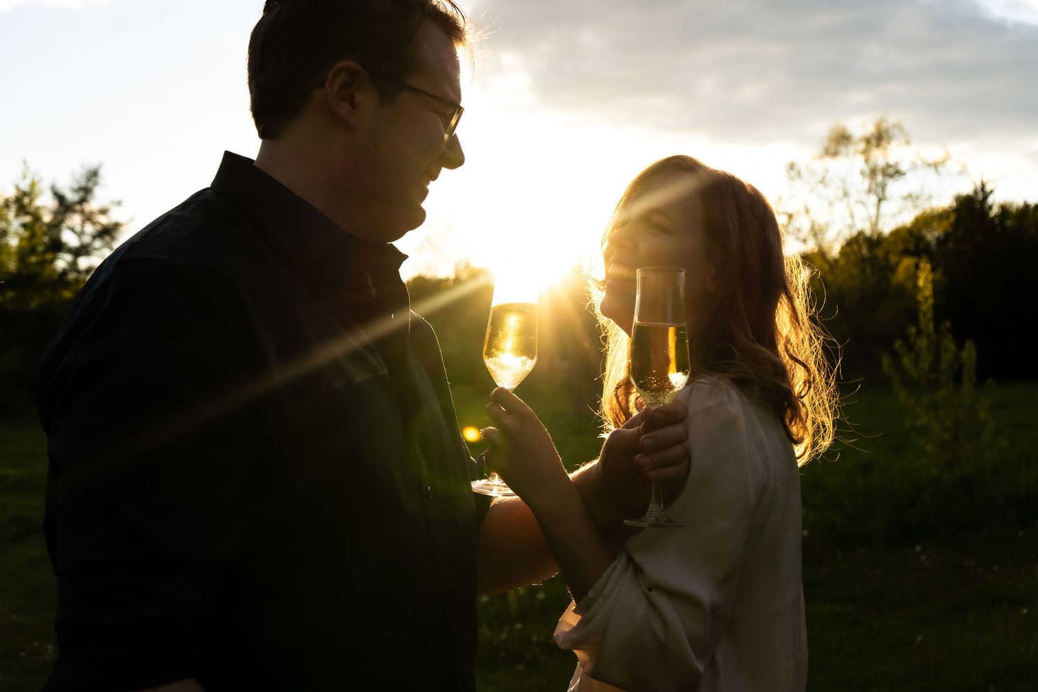 A couple silhouetted against a golden sunset in a romantic outdoor setting.