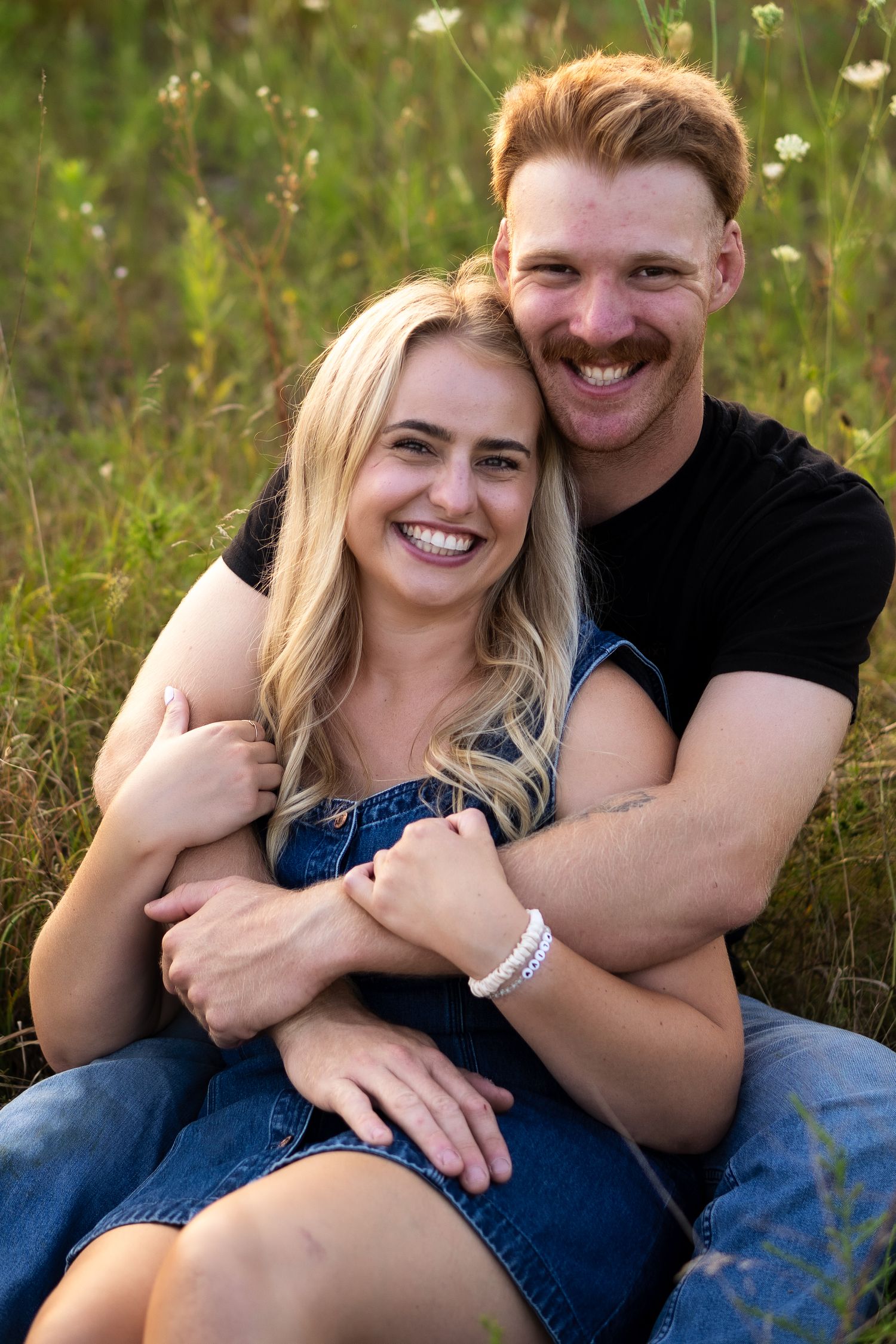 couple smile at camera while cuddled together