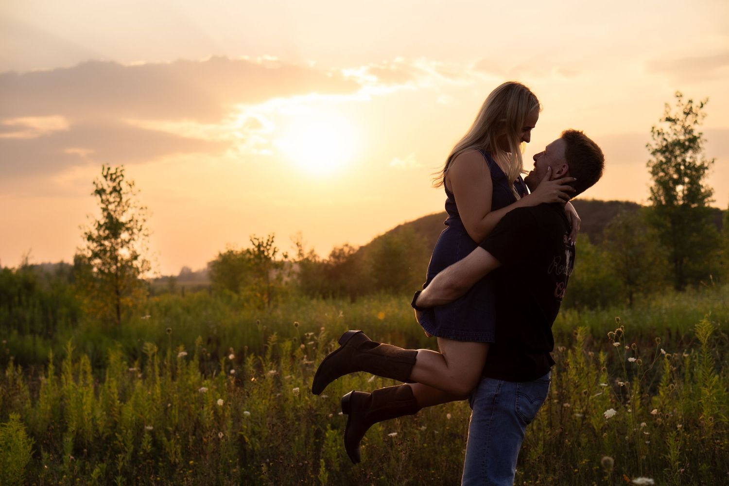 man lifts women up and spins with the sunset