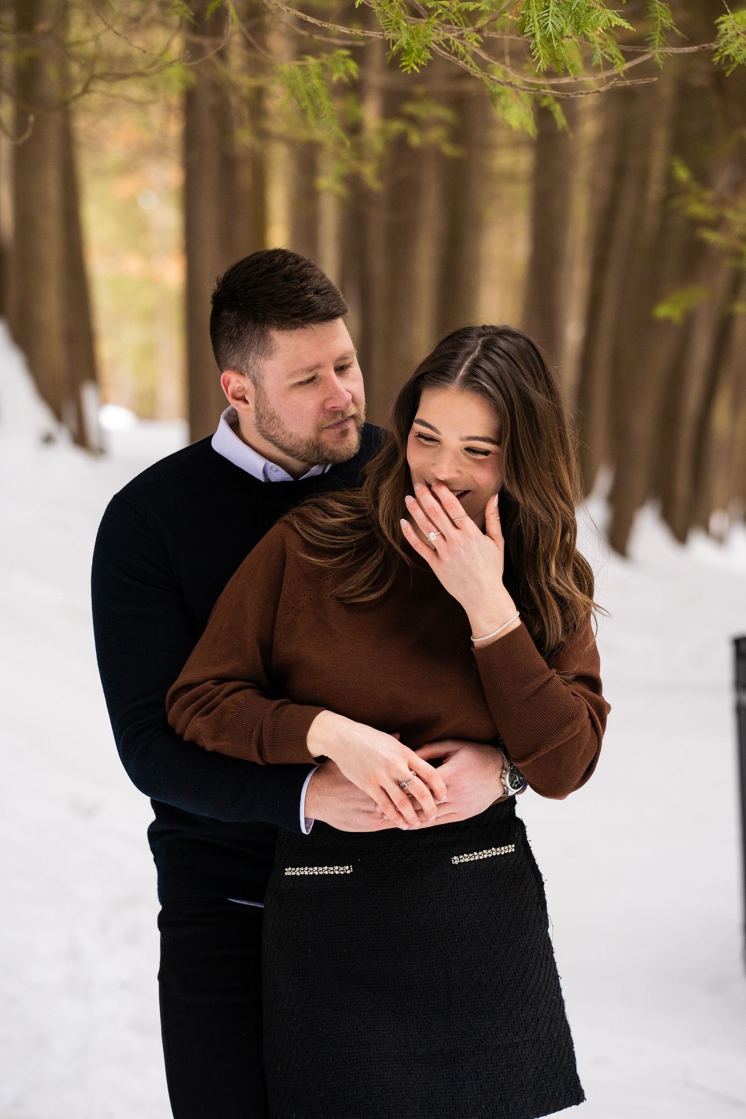 Women laughs and covers mouth while man looks on lovingly