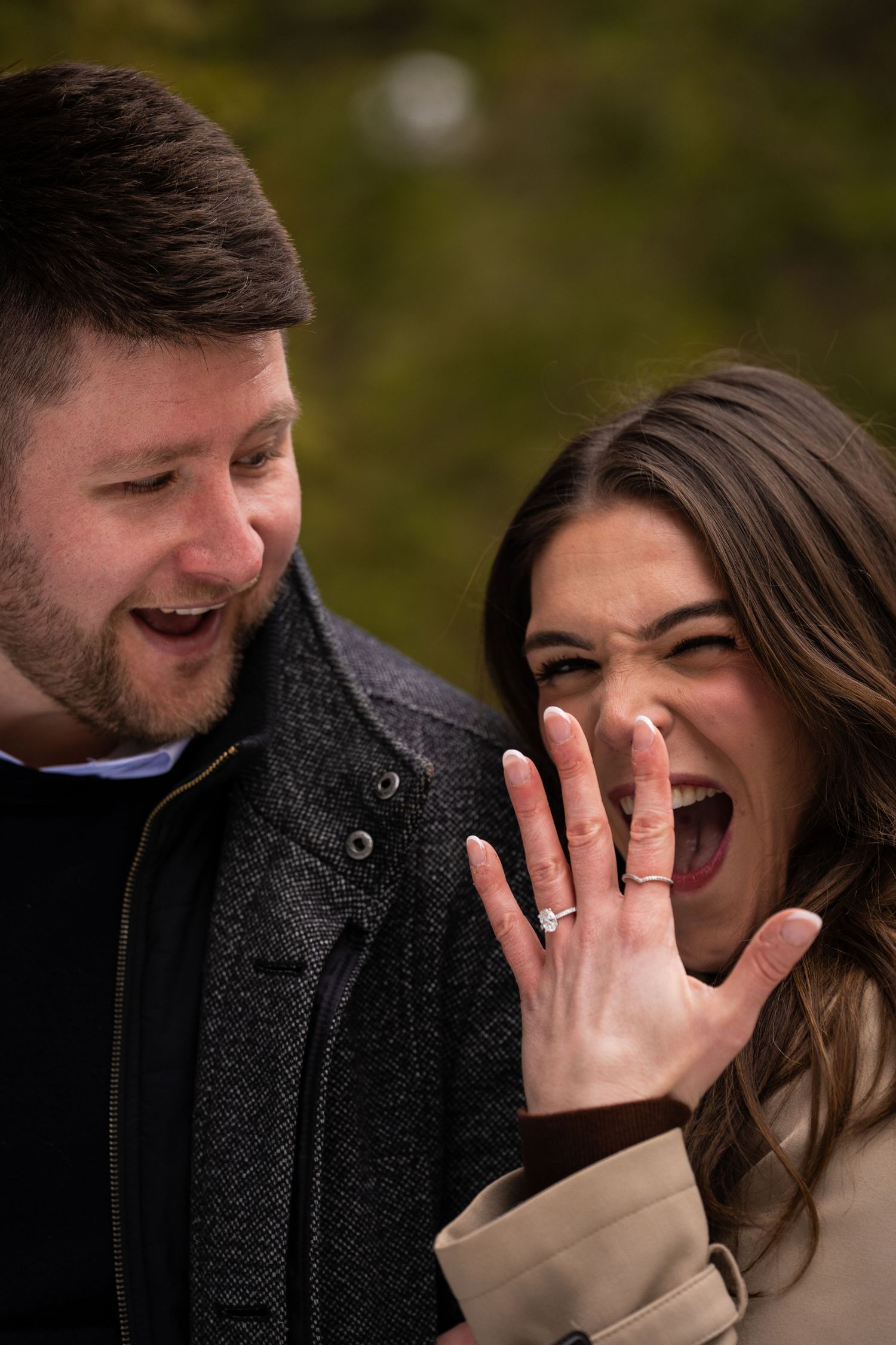 A couple shares a joyful candid moment together while laughing during an outdoor photo session.