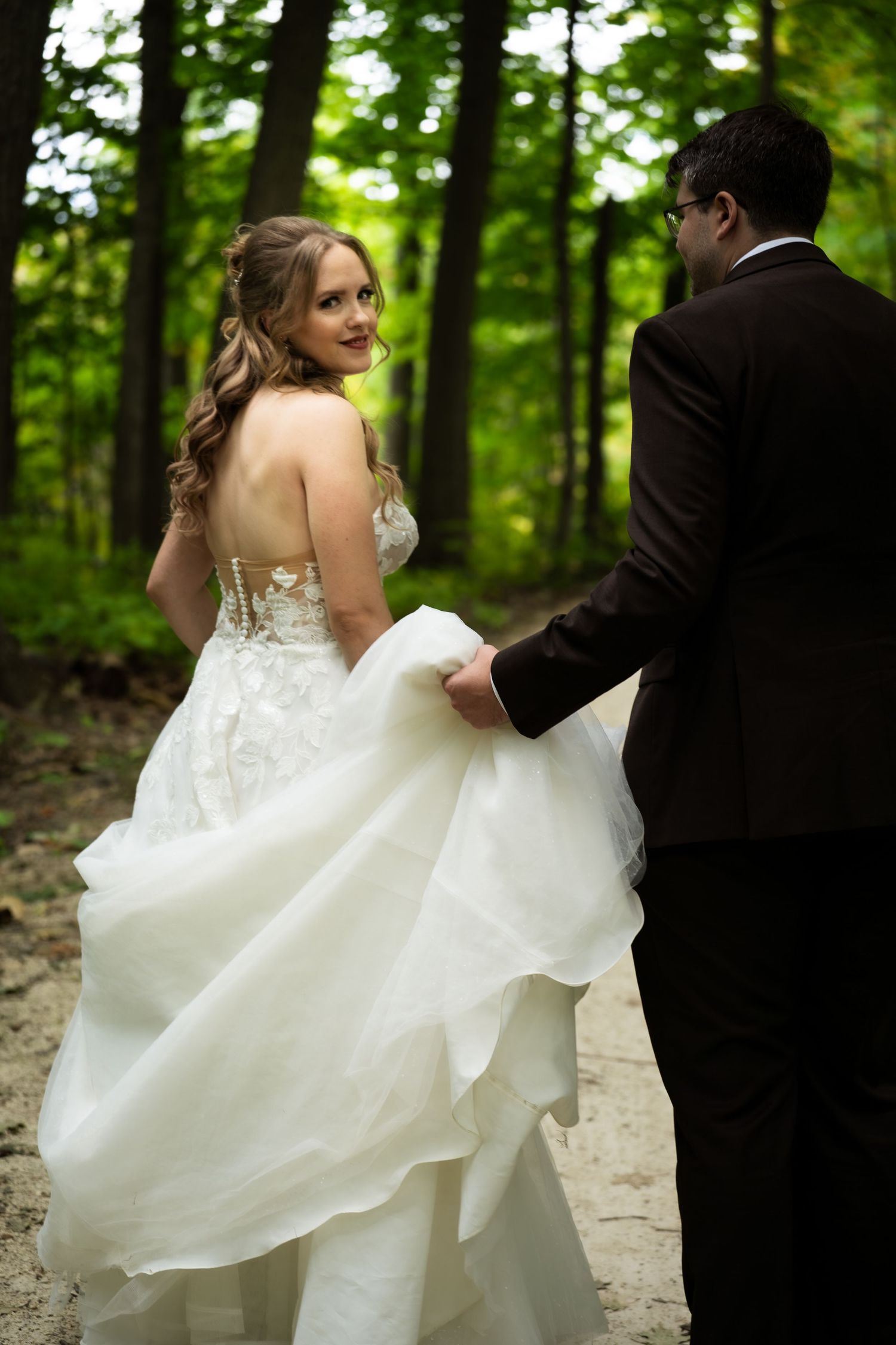 bride looks back at camera while groom carries her train