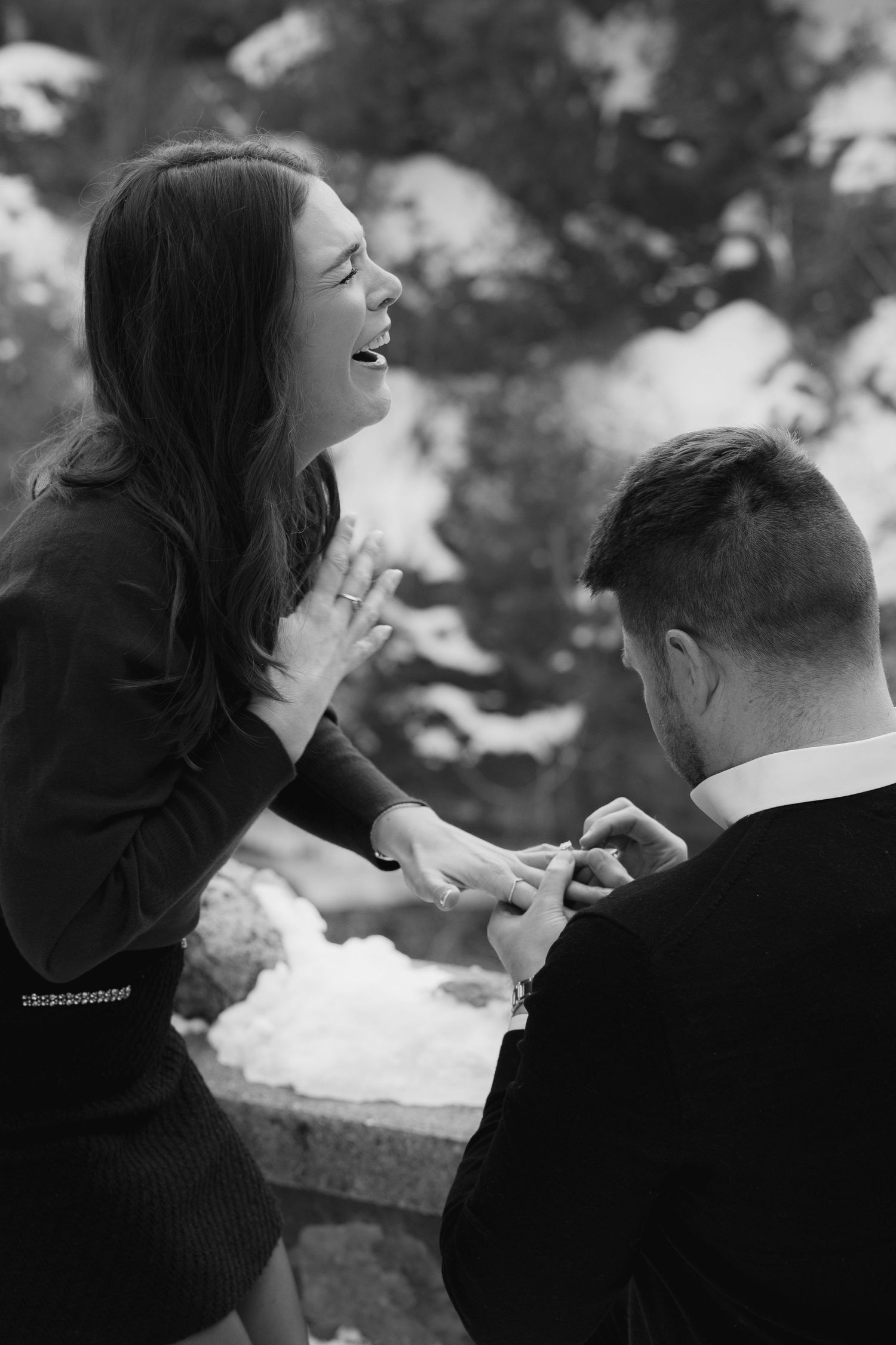 Black and white photo series showing a couple laughing and embracing in a romantic outdoor setting.