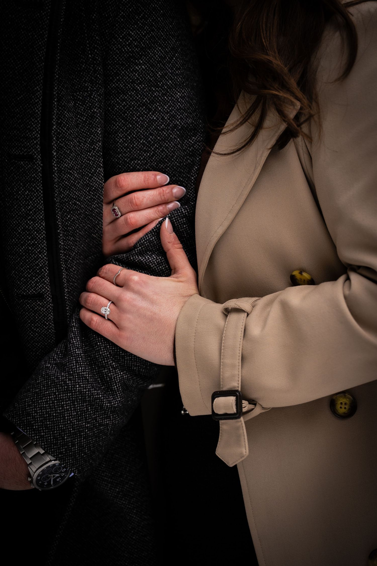 Close-up sequence showing hands gently caressing a beige blazer sleeve against a dark background.