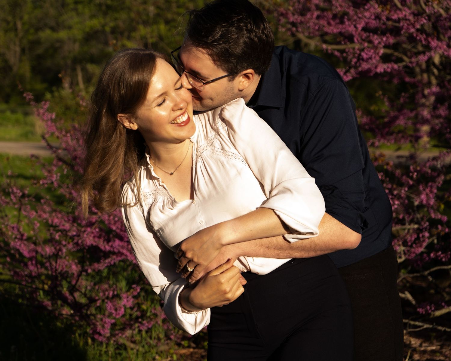 Romantic couple embracing among blooming cherry blossoms at sunset.