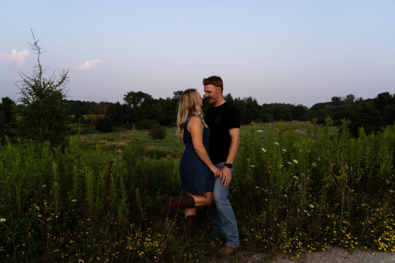 couple look at each other with large field and tree vista in the background