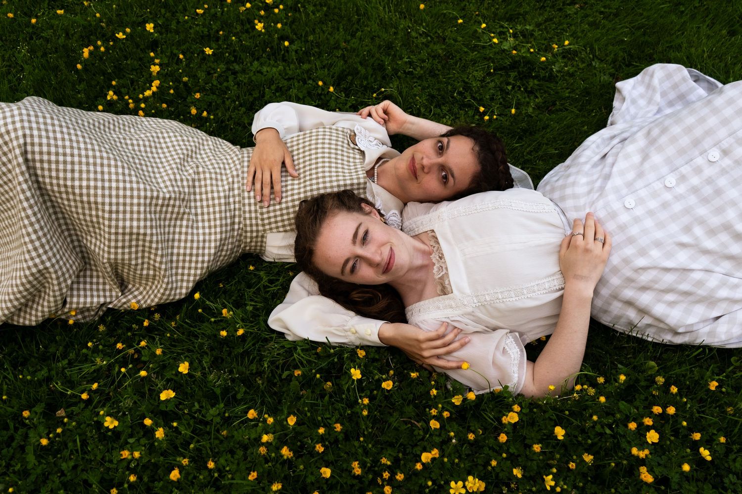 A person lying on grass scattered with yellow dandelions on a sunny day.