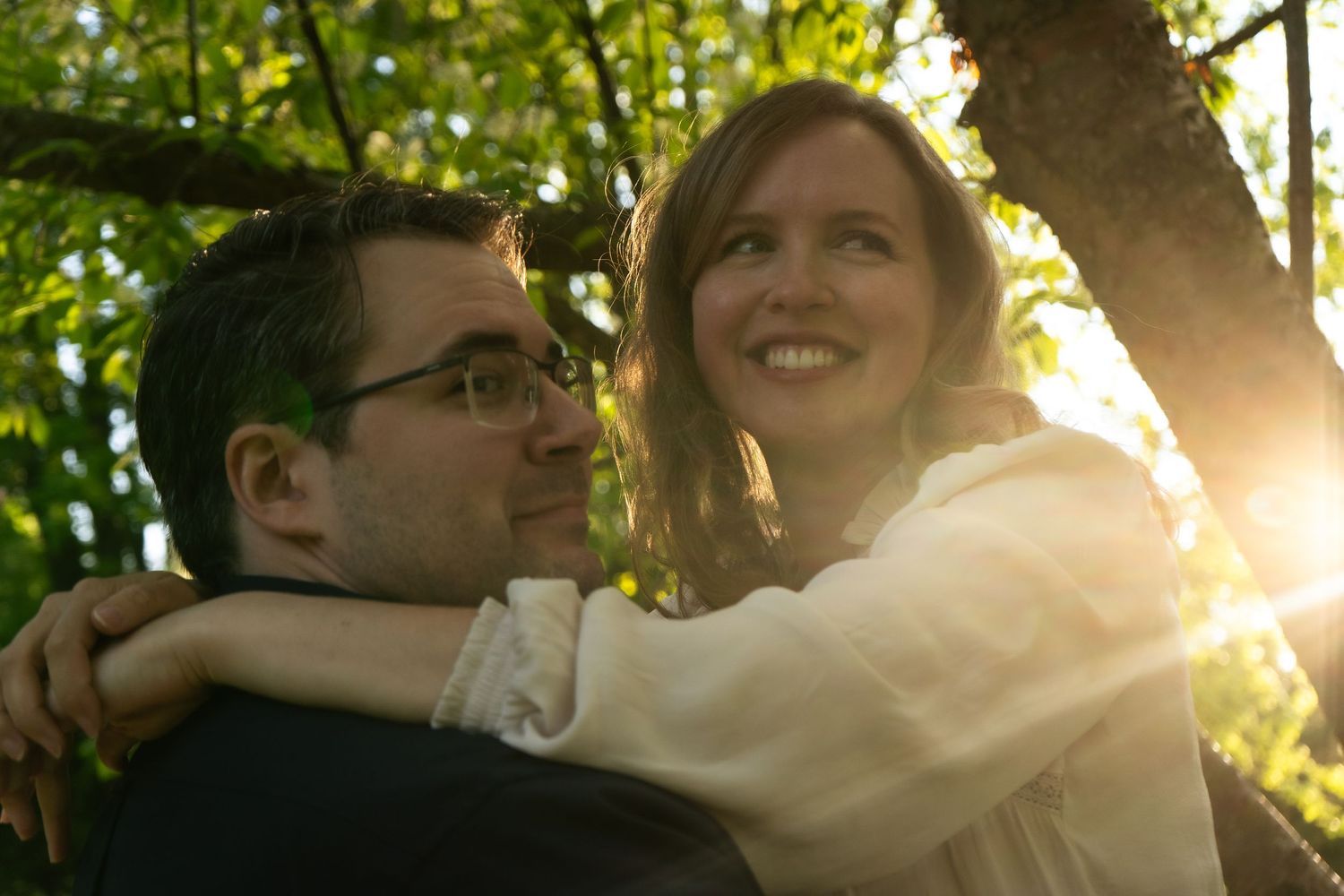 Couple sharing intimate moment in sunlit garden with golden hour glow.